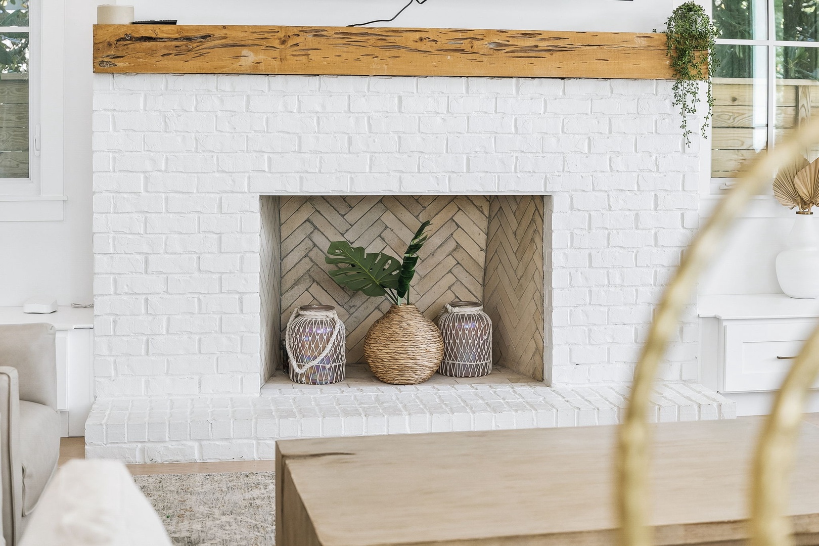 Cozy up by your charming white brick fireplace, topped with a rustic wooden mantel and styled with natural decor that brings warmth and coastal calm to your relaxing retreat.