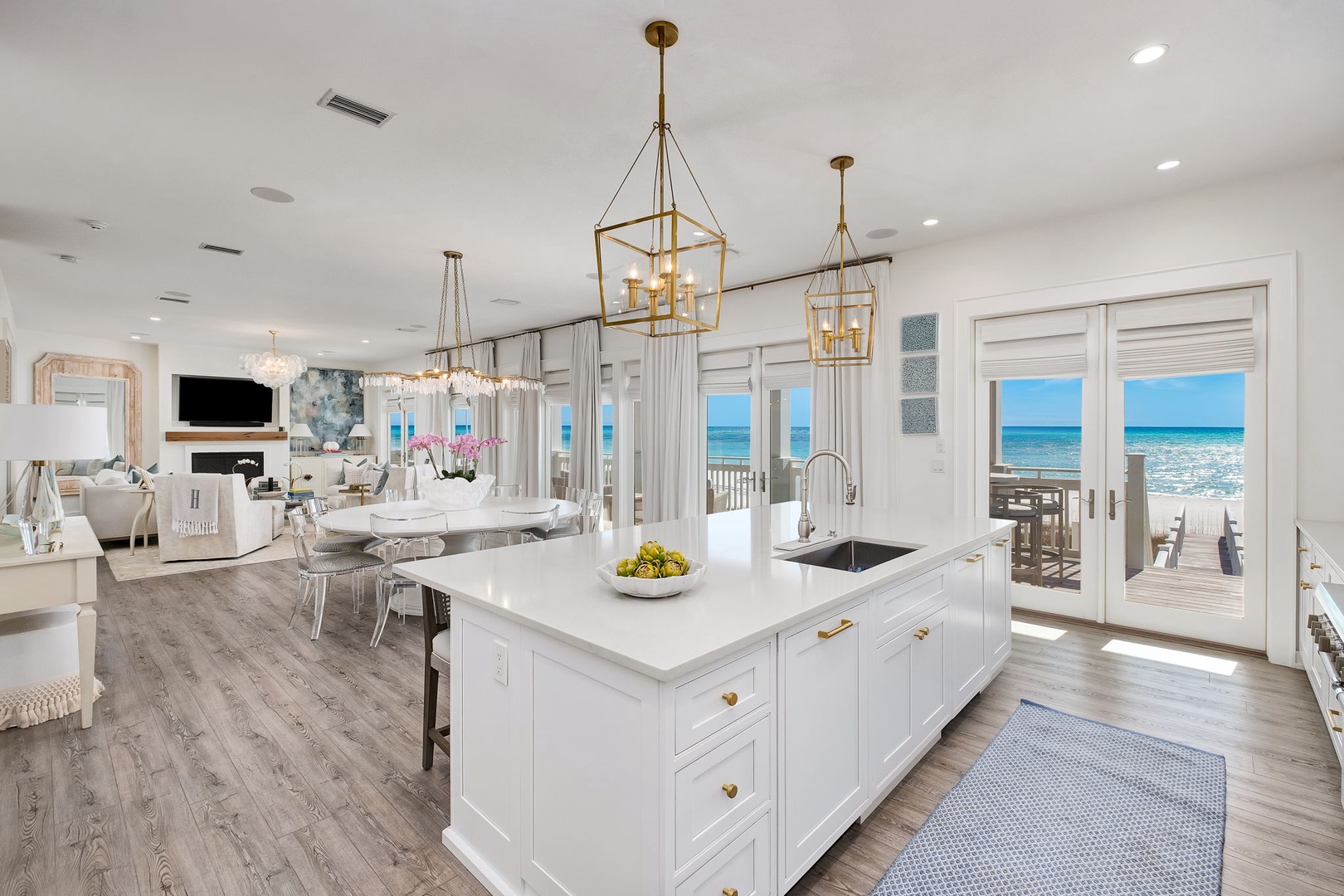 Picture yourself cooking in this stunning coastal kitchen, where golden chandeliers illuminate your countertops and ocean breezes drift through the doors. Bright, open, and inviting—you'll love the sunny space that flows seamlessly to the sea.