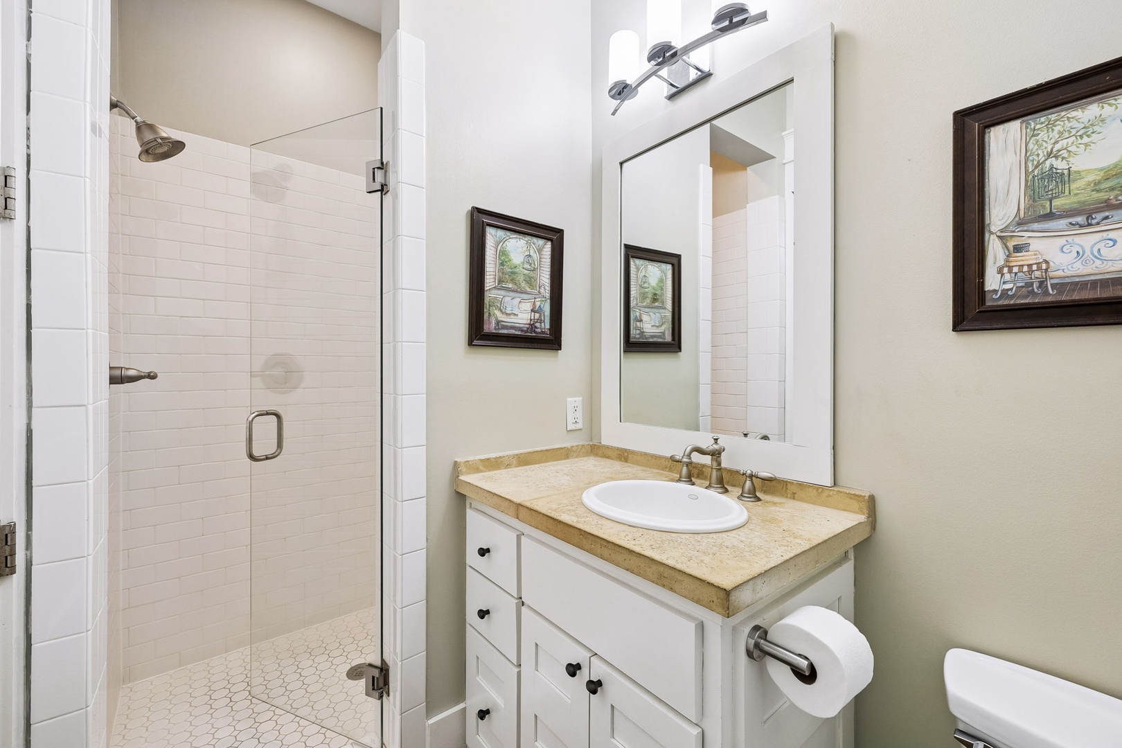 Your bathroom features a bright, walk-in shower with gleaming white subway tile, a vanity with warm stone countertops, and charming farmhouse details—all designed to help you feel refreshed and right at home.