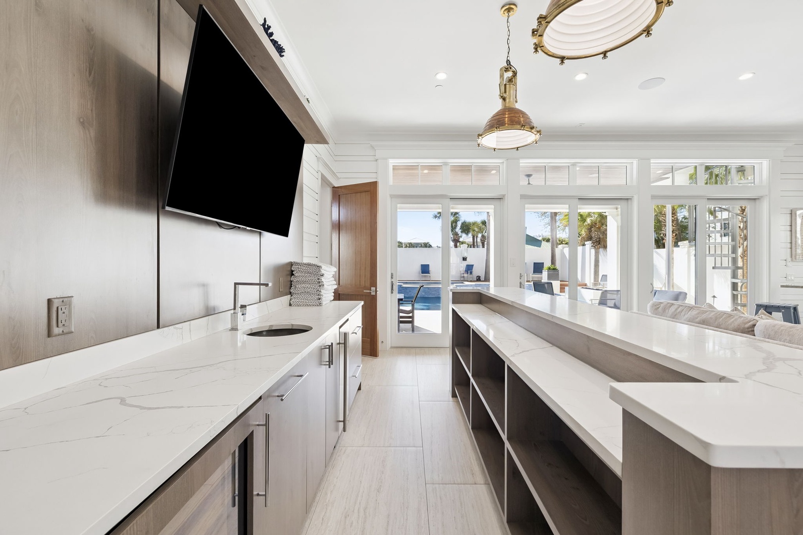 Cook in your luxury kitchen with pristine marble countertops, modern appliances, and stunning pool views through expansive windows.