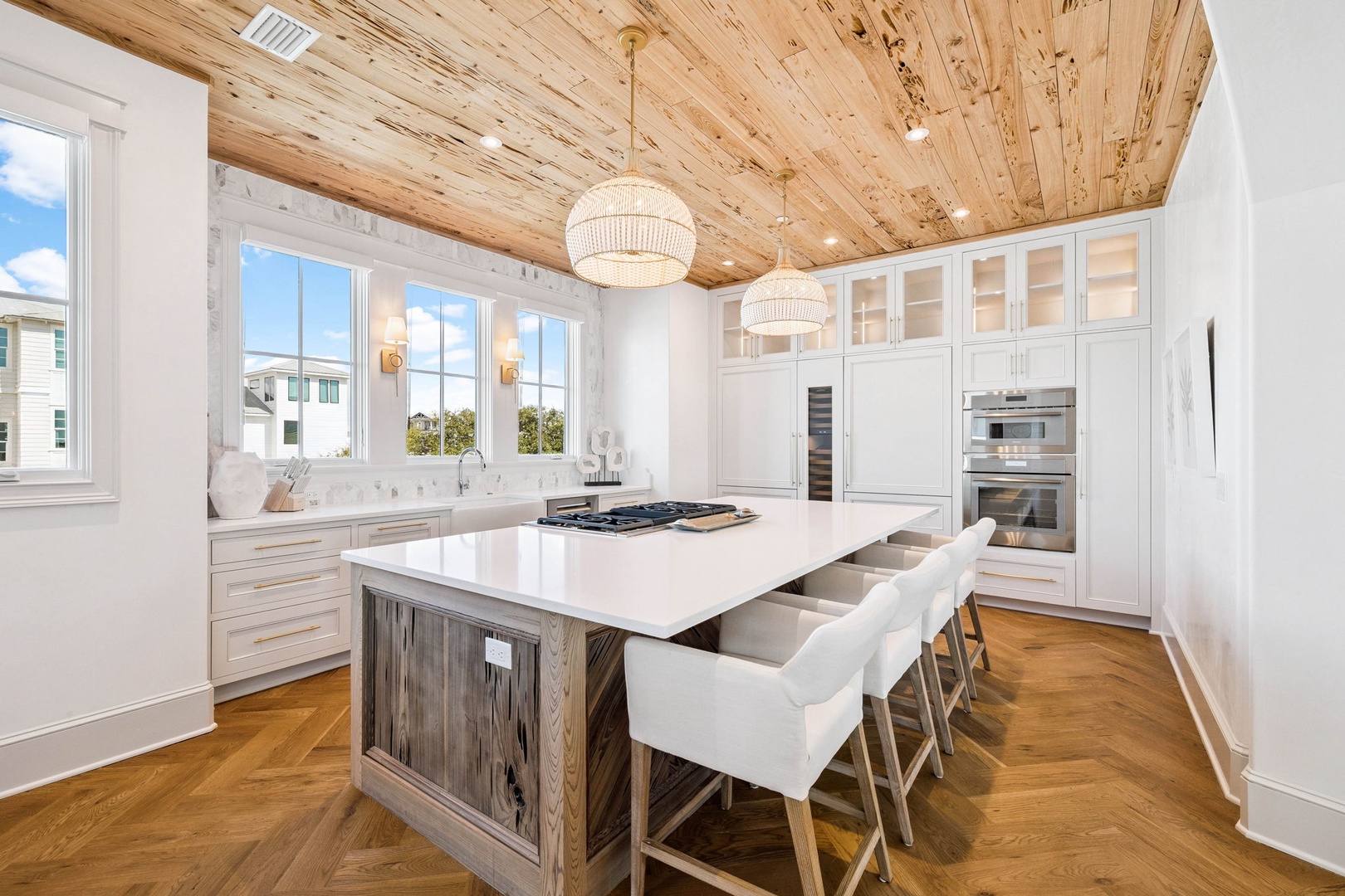 Gather around the sleek island in your gourmet kitchen, where gleaming countertops, top-tier appliances, and stunning wood-paneled ceiling create the perfect space for cooking and conversation.