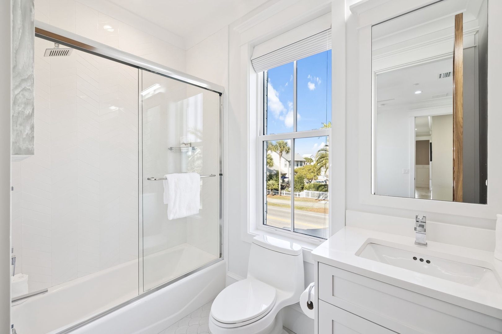 Freshen up in your bright marble bathroom with walk-in shower and natural light streaming through the window.