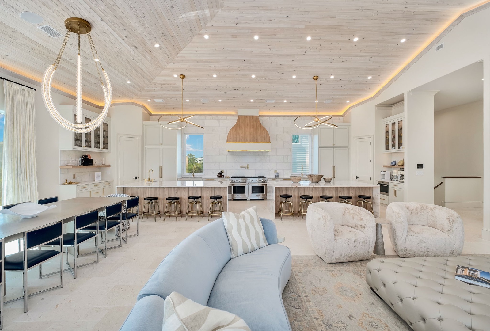 Gather in this stunning open-concept space where natural wood ceilings and designer lighting create a warm, inviting atmosphere. The spacious kitchen and cozy seating areas blend seamlessly for your perfect retreat.