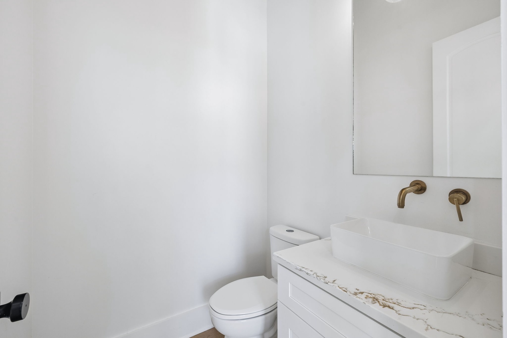 Freshen up in your modern bathroom with a sleek vessel sink, elegant marble countertop, and polished bronze fixtures that add a warm, sophisticated touch.