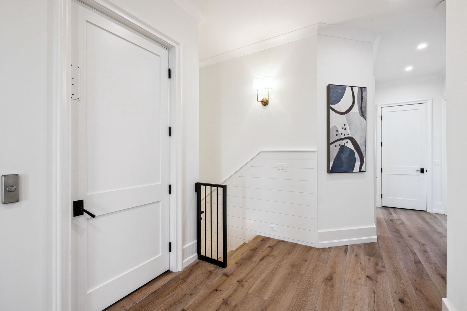 Step into your stylish hallway with warm hardwood floors, crisp white walls, and modern artwork that creates a welcoming arrival experience.