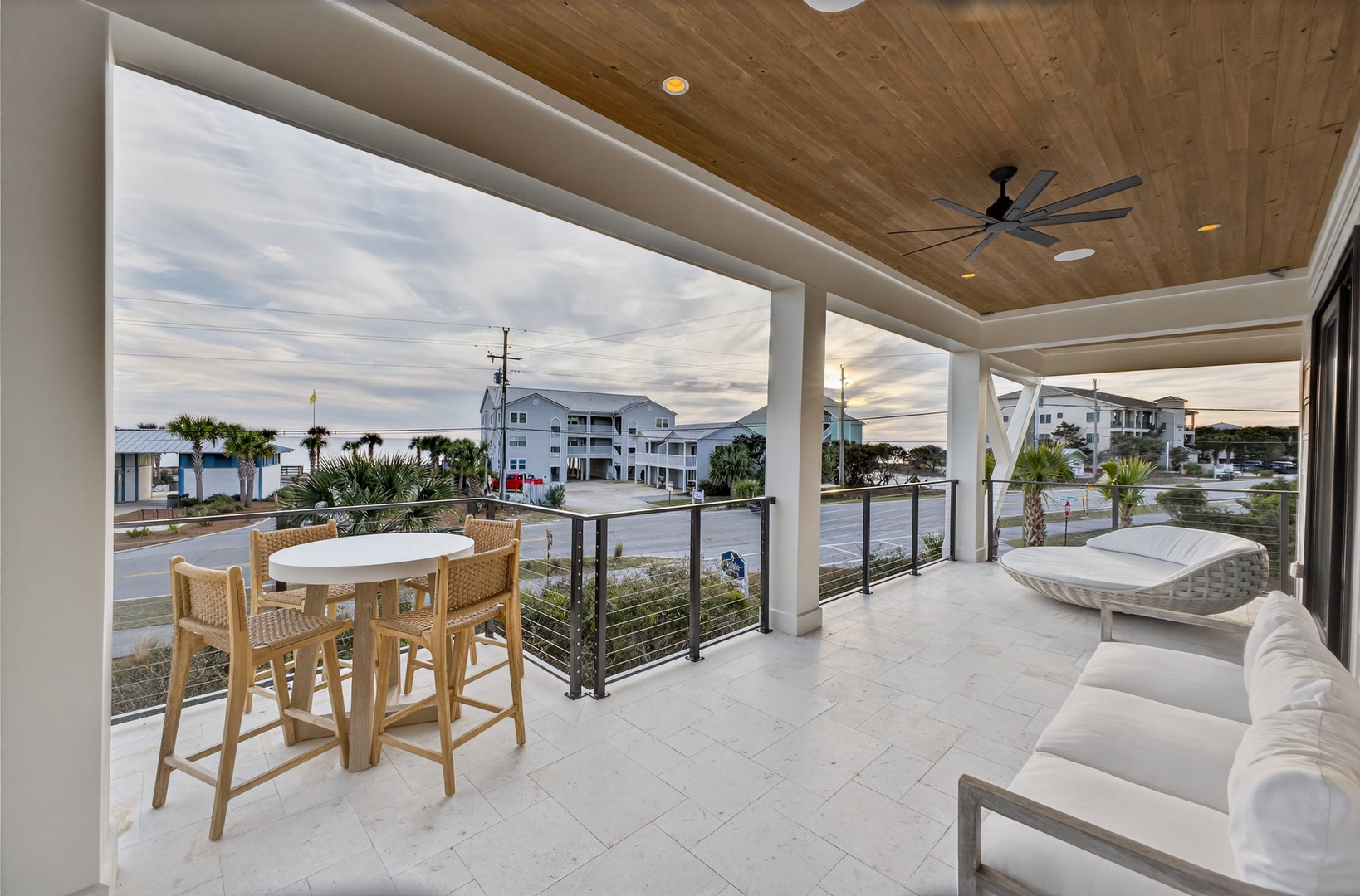Unwind on your private covered terrace with ceiling fans, comfortable seating, and dining space overlooking the coastal neighborhood.