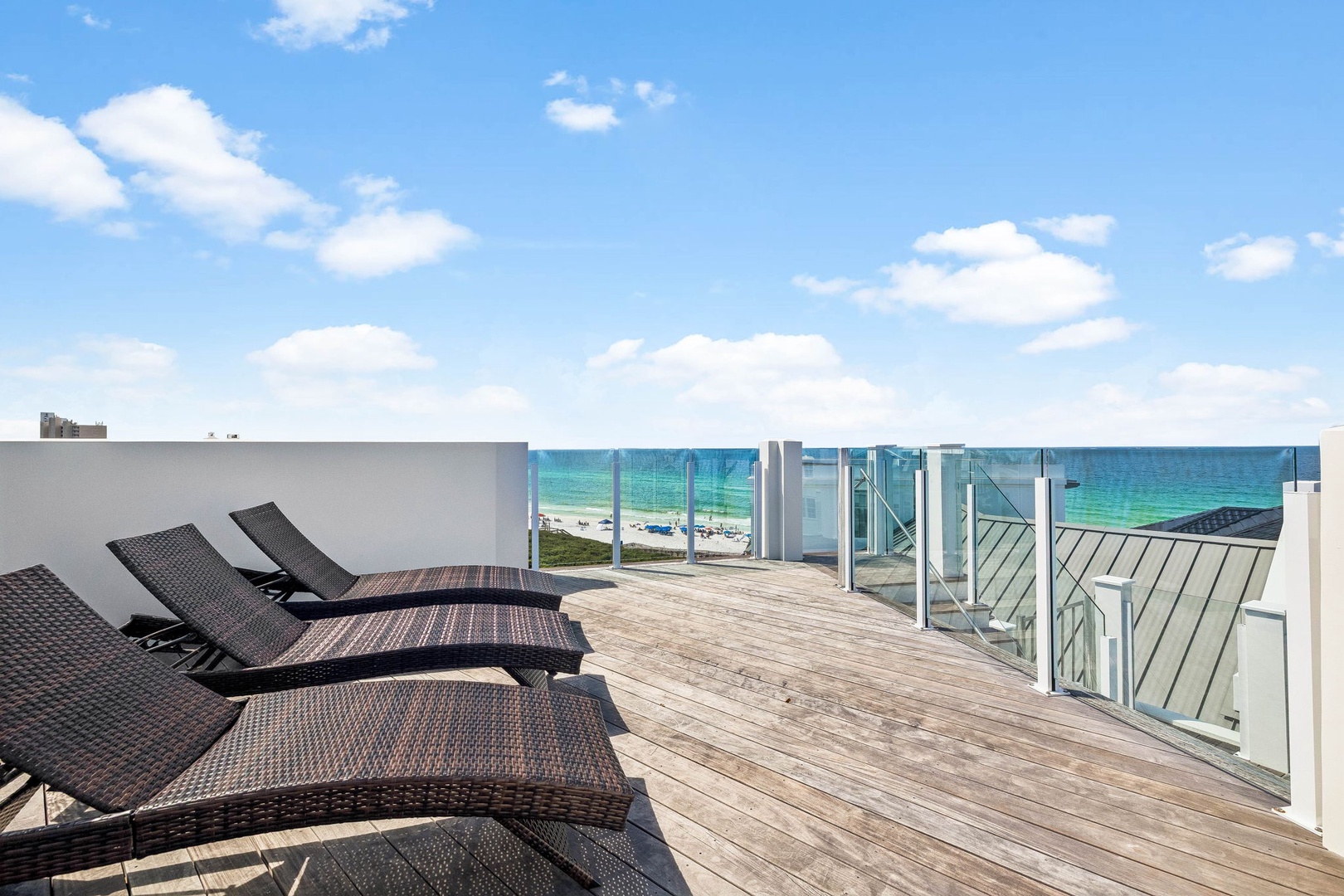 Rooftop terrace overlooking pristine turquoise waters and sandy shores, featuring sun loungers for soaking up the coastal breeze and endless ocean views.