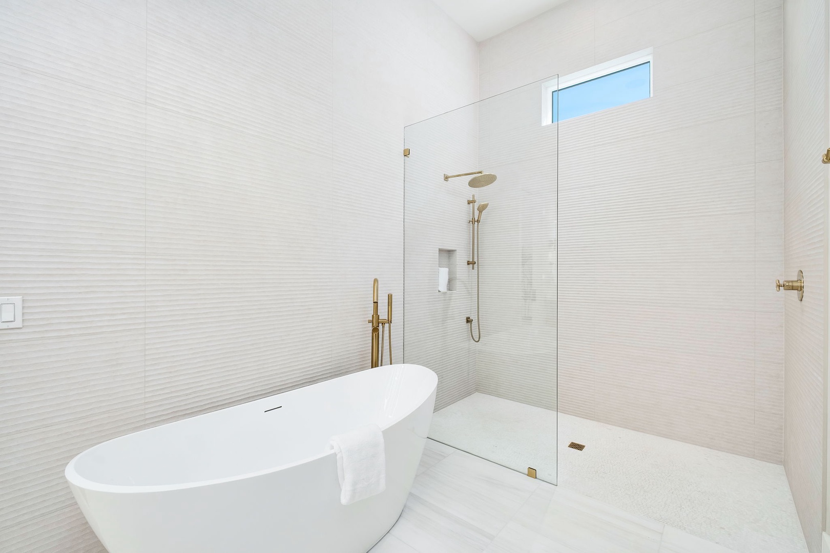 Step into your sleek, spa-inspired bathroom featuring a luxurious freestanding tub and spacious walk-in shower with elegant brass fixtures, perfect for unwinding after your adventures.