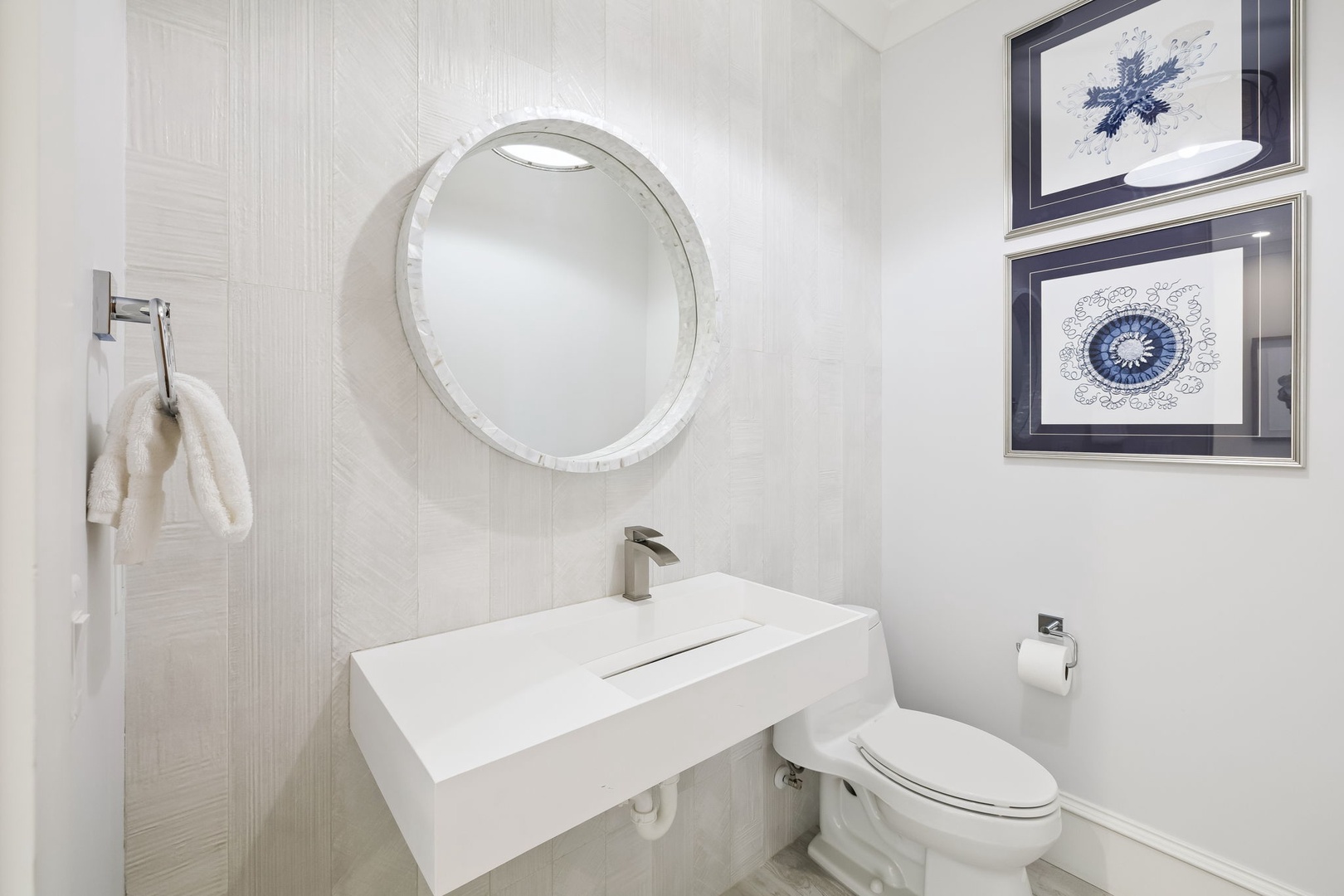 Freshen up in your sleek powder room featuring a modern floating vanity, circular mirror, and crisp white finishes.