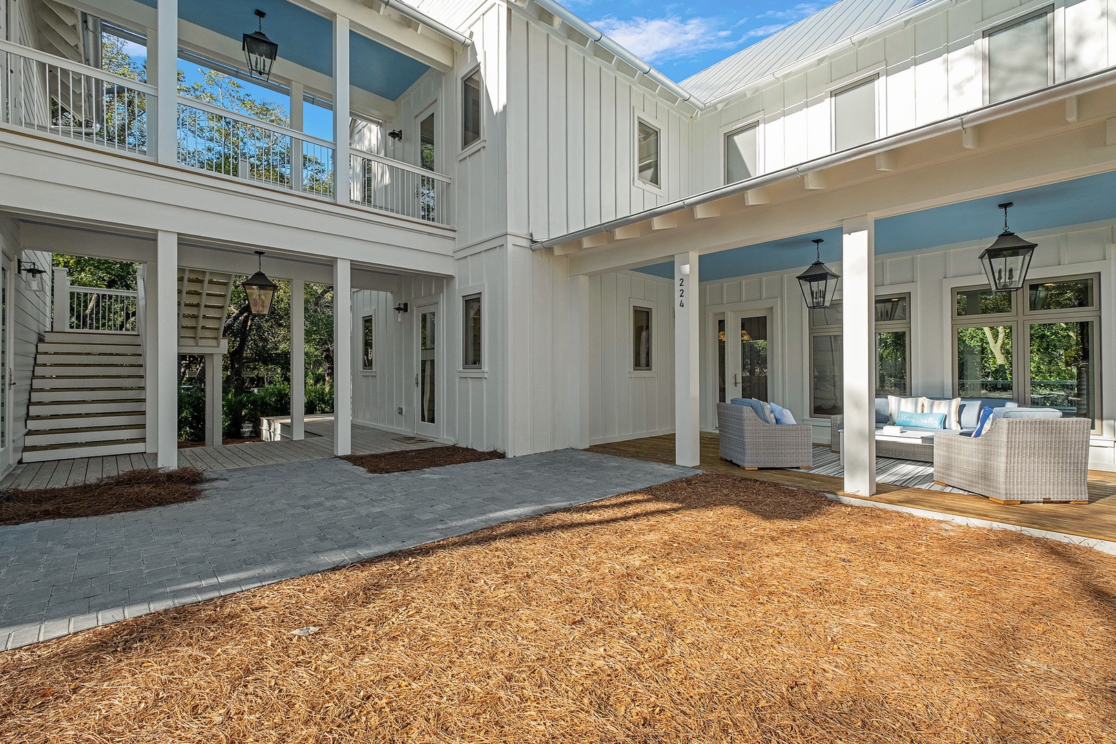 Modern coastal architecture features a stunning courtyard design with clean white siding and elegant outdoor seating areas.
