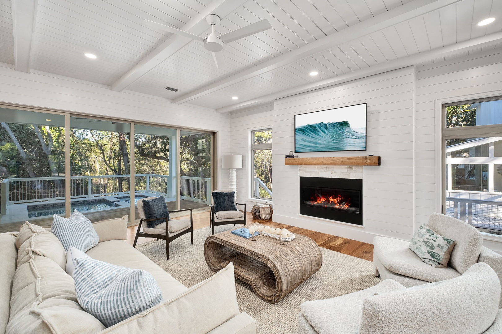 Unwind in your elegant living room featuring a cozy fireplace and stunning tree-lined views through floor-to-ceiling windows.