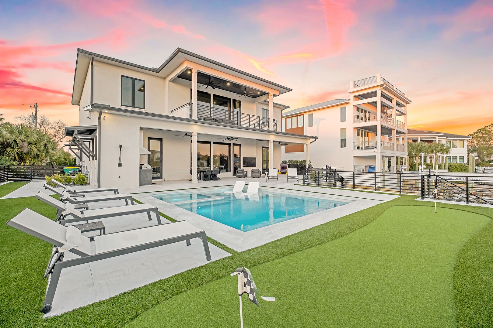 Modern vacation rental showcasing pristine pool, manicured lawn, and contemporary architecture during golden hour.