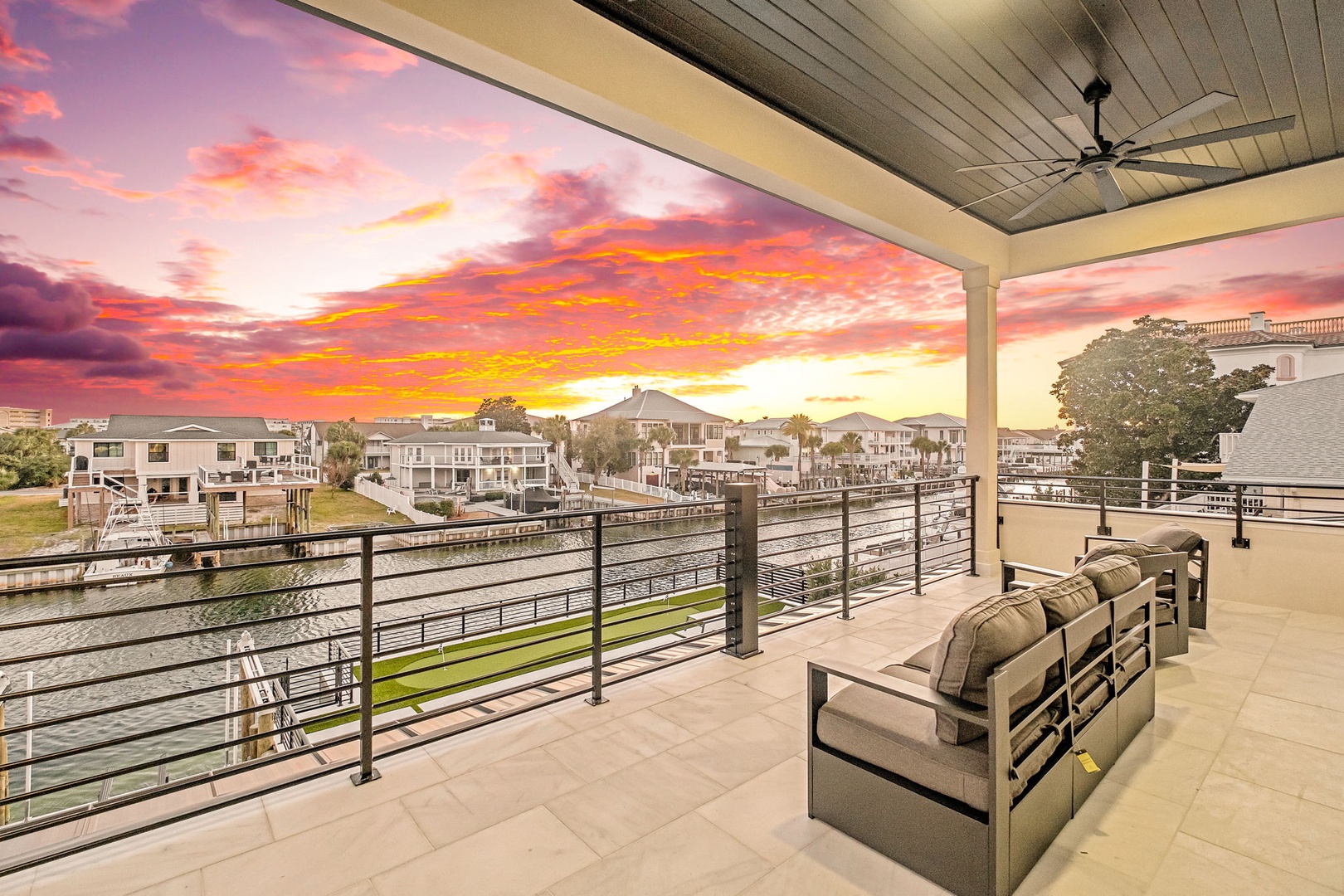 Unwind on your private covered terrace as vibrant sunset colors paint the sky above this peaceful waterfront community.
