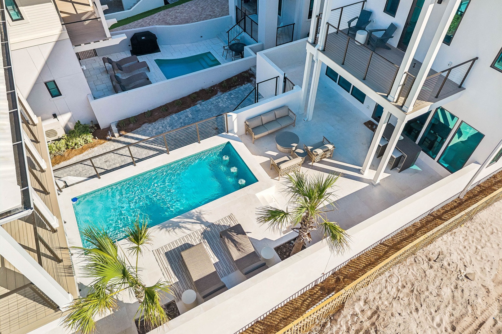 Modern beachfront architecture with a private pool, sun loungers, and tropical palms just steps from the sand—your perfect coastal escape awaits.