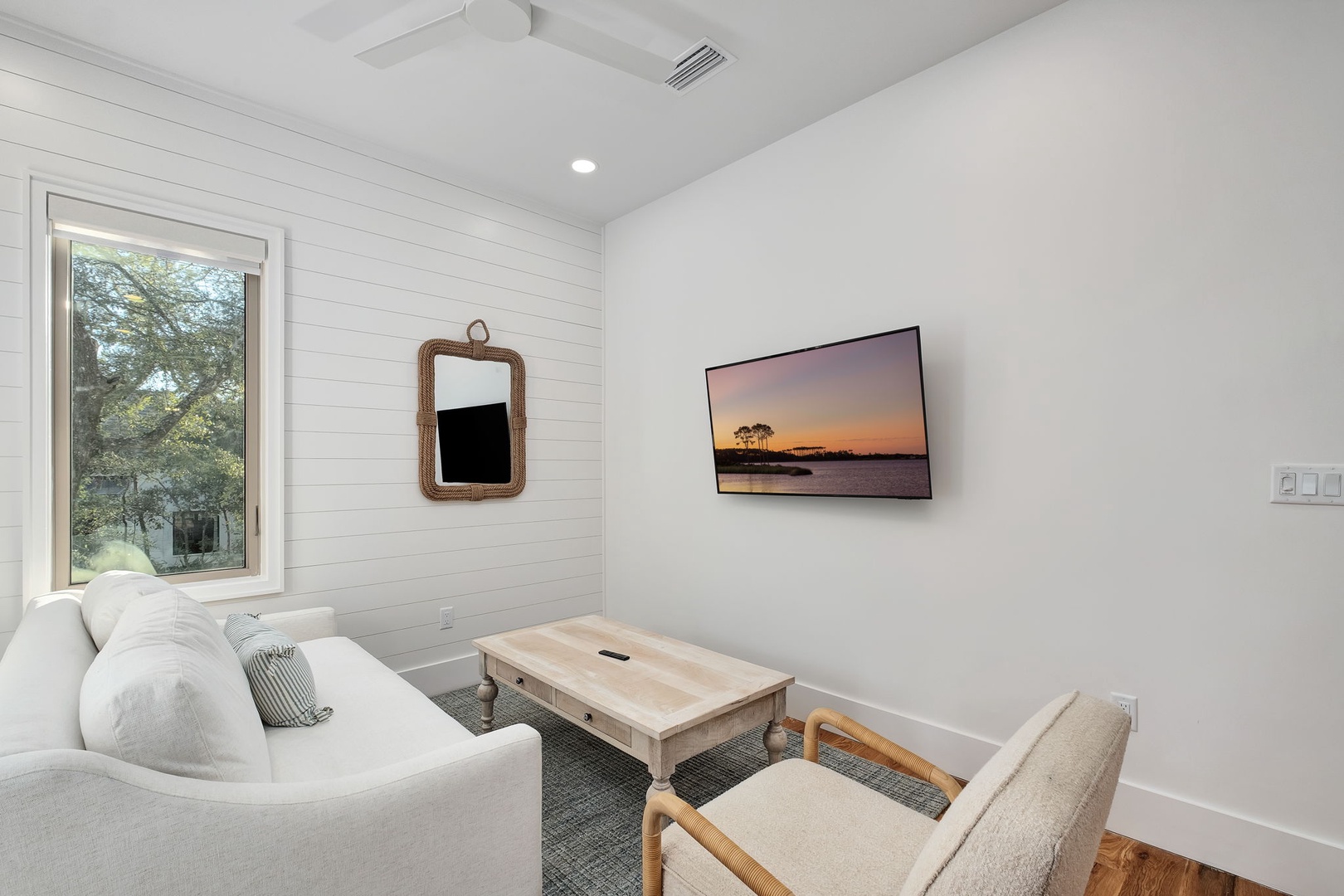 Relax in your bright, modern living space featuring cozy seating and a wall-mounted TV for entertainment.