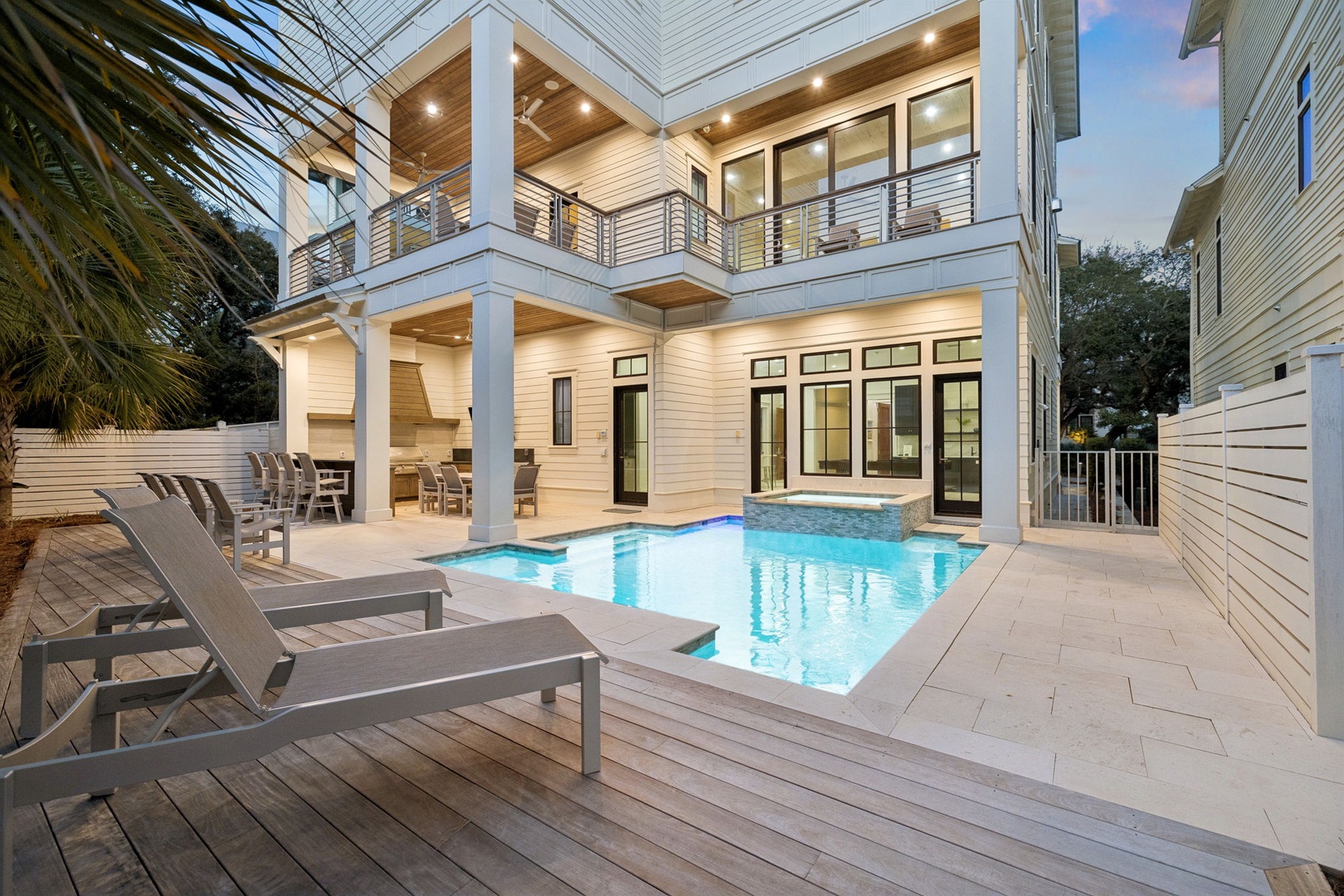 Modern two-story vacation home featuring a private swimming pool surrounded by comfortable lounge chairs and covered outdoor dining area.