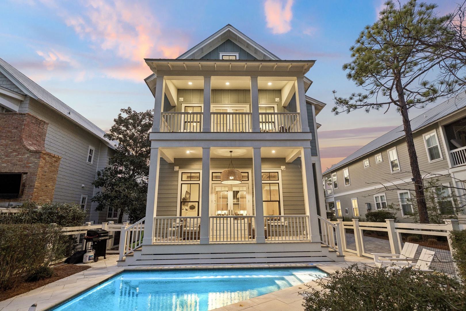 Elegant two-story vacation home with private pool, featuring classic architecture and modern lighting in a peaceful residential setting.