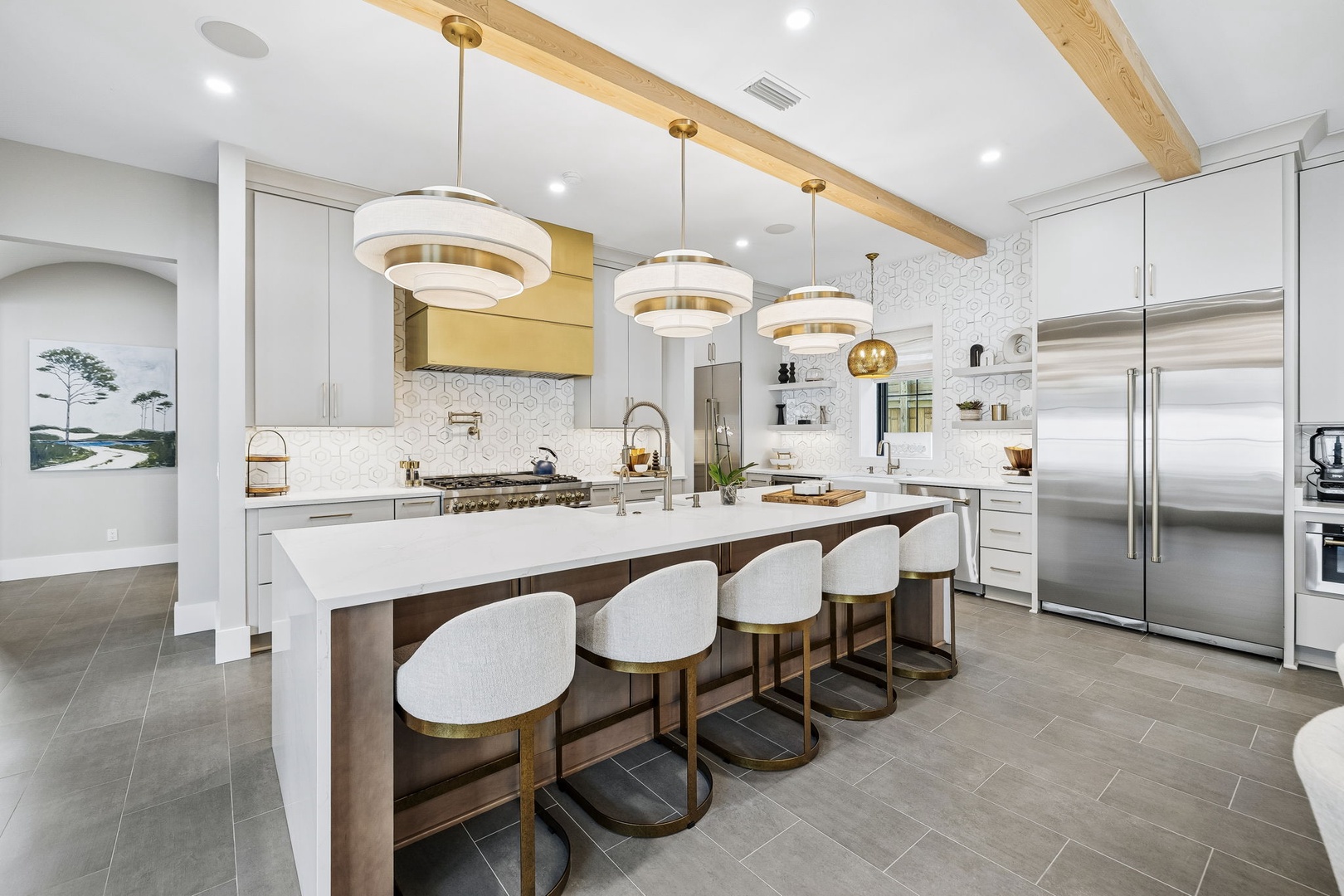 A sleek, modern kitchen awaits with gleaming countertops, custom cabinetry, and a spacious island perfect for cooking and conversation. Warm wood beam accents and elegant pendant lighting create an inviting ambiance for your stay.