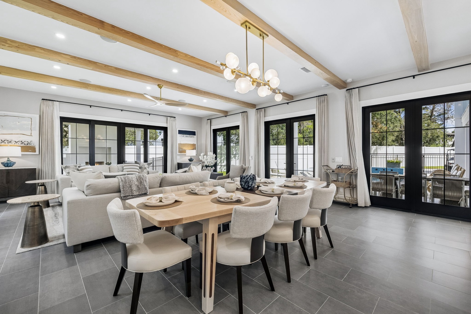 Gather your group around this elegant dining table beneath warm exposed beams, where modern elegance meets effortless comfort. Beyond the glass doors, you'll find inviting outdoor spaces perfect for relaxing after a day of exploring.