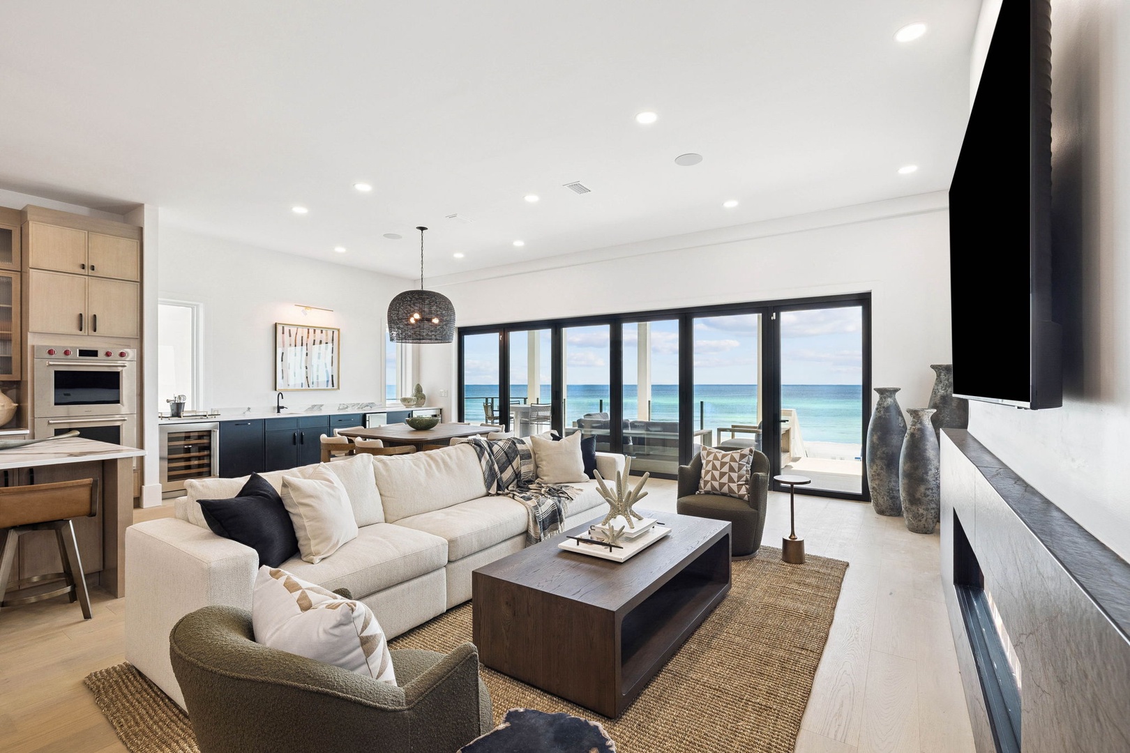 Your open-plan retreat flows seamlessly from kitchen to living area, with floor-to-ceiling glass doors framing stunning ocean views—the perfect backdrop for unwinding after a day at the beach.