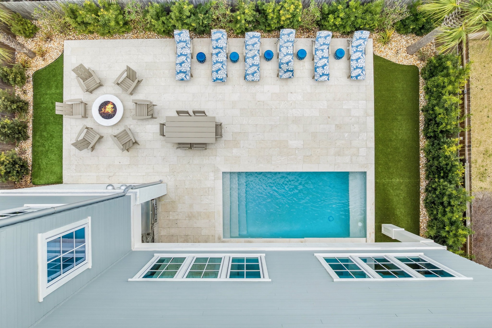 Aerial view of a modern property featuring a pristine swimming pool, outdoor dining area, and manicured grounds with tropical landscaping.