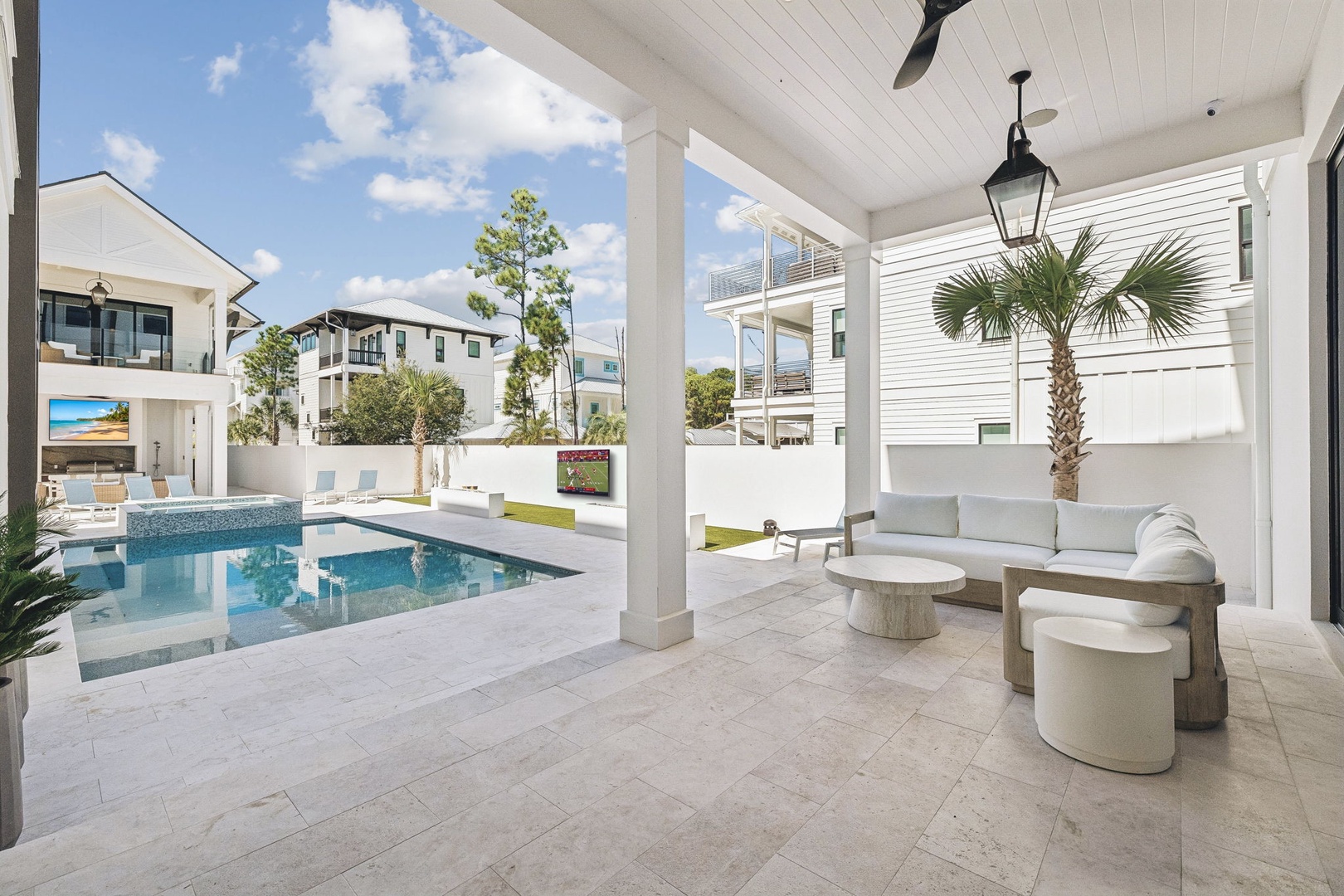 A modern coastal property featuring a sparkling pool surrounded by contemporary architecture, palm trees, and bright blue skies—a serene backdrop for your vacation escape.