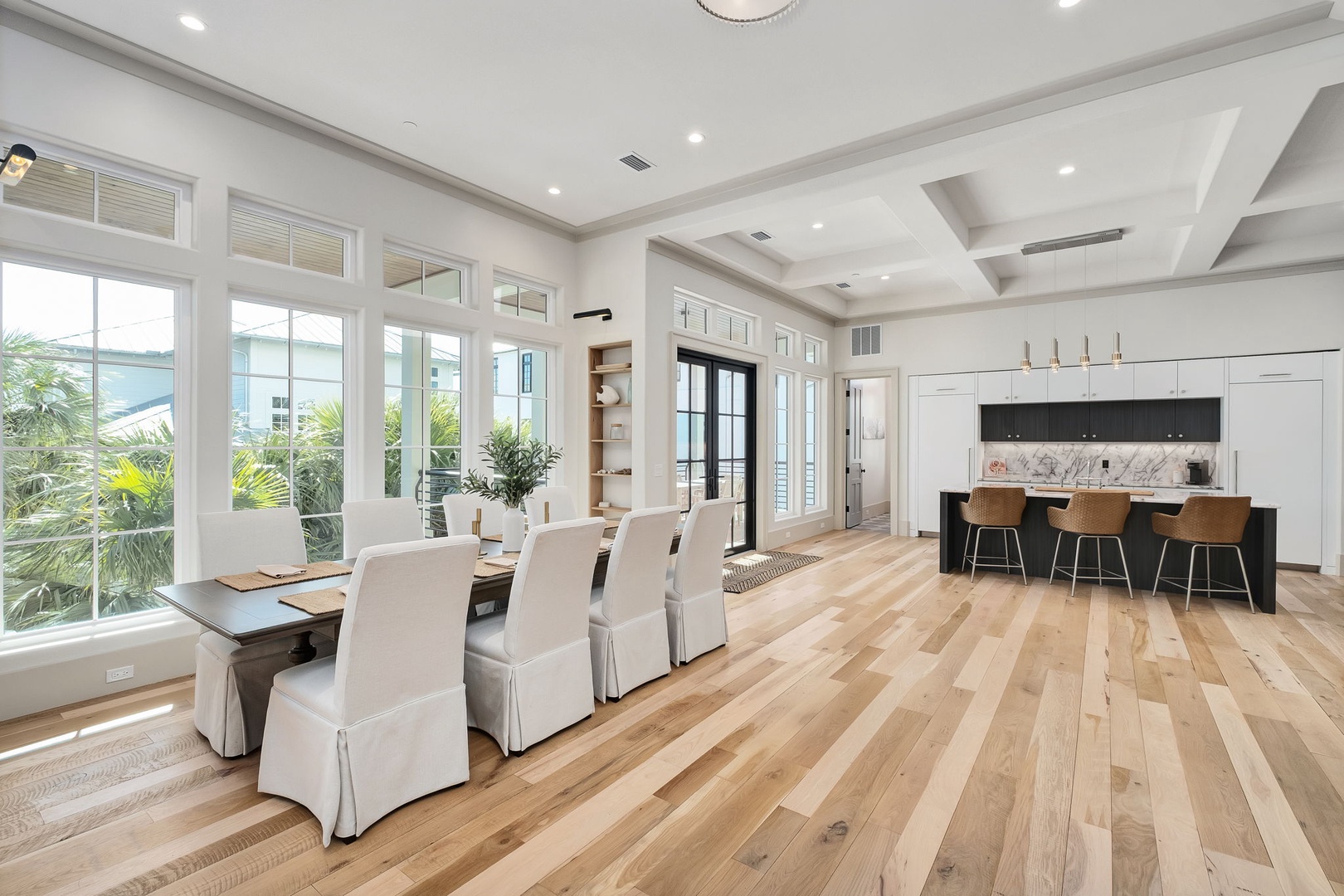 Your bright open-plan space flows seamlessly from dining to kitchen, with natural light streaming through windows and warm wood floors underfoot.