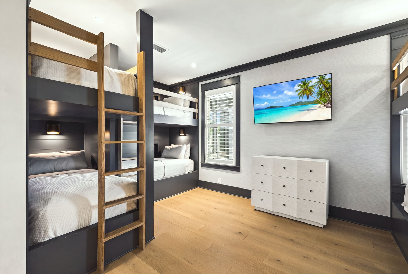 Modern bunk beds offer cozy sleeping nooks with individual reading lights, perfect for friends or family traveling together. Natural wood accents warm the space while a dresser provides ample storage for your belongings.