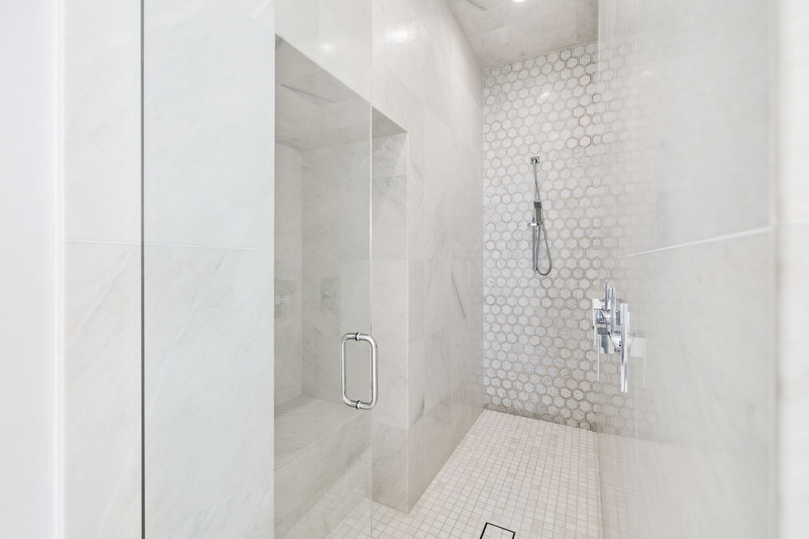 Step into your luxurious walk-in shower with elegant hexagonal tiling and premium fixtures for an indulgent bathing experience.