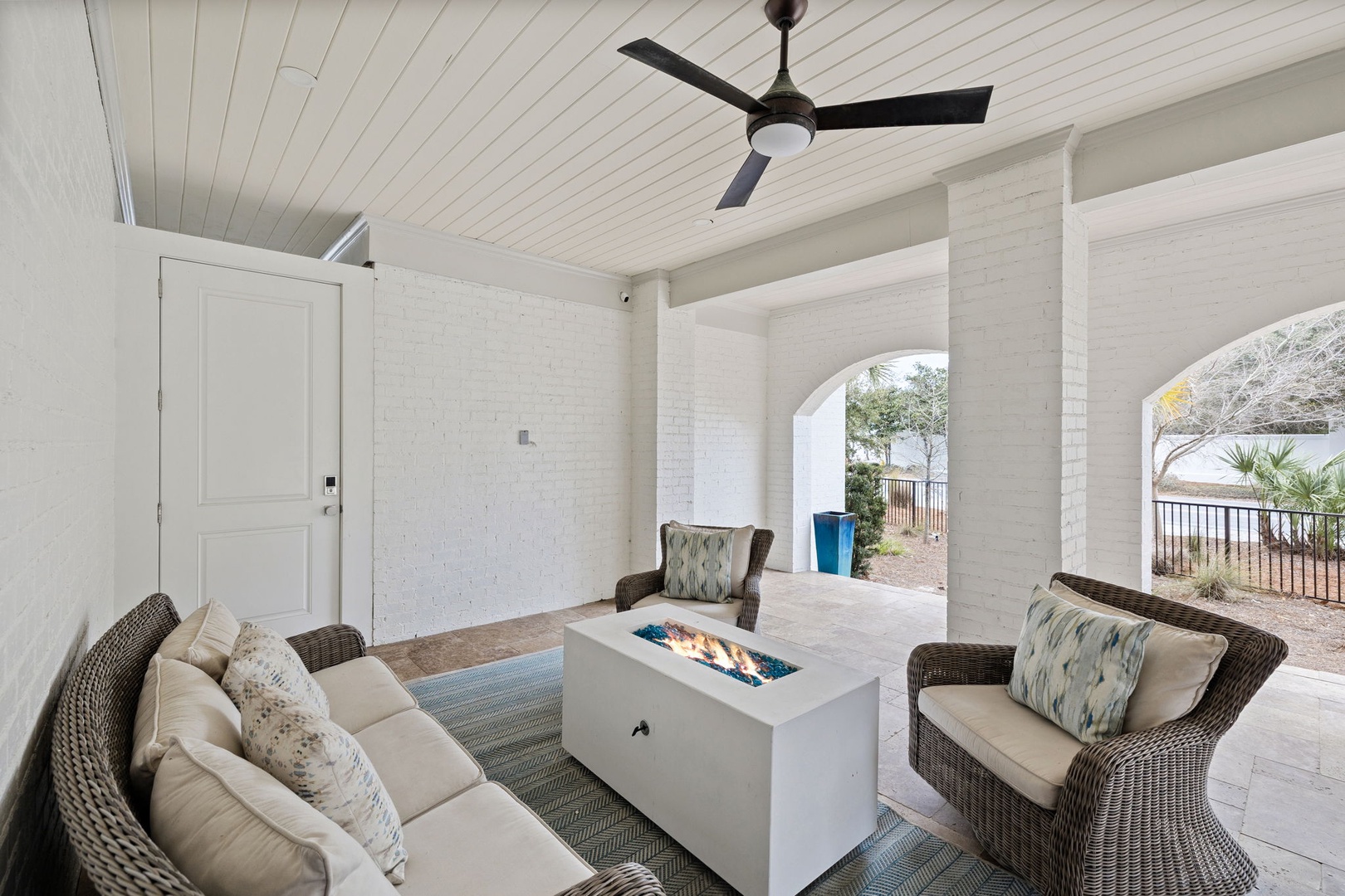 Unwind in your private patio lounge with cozy seating and a warm fire table, perfect for evening relaxation under the ceiling fan.