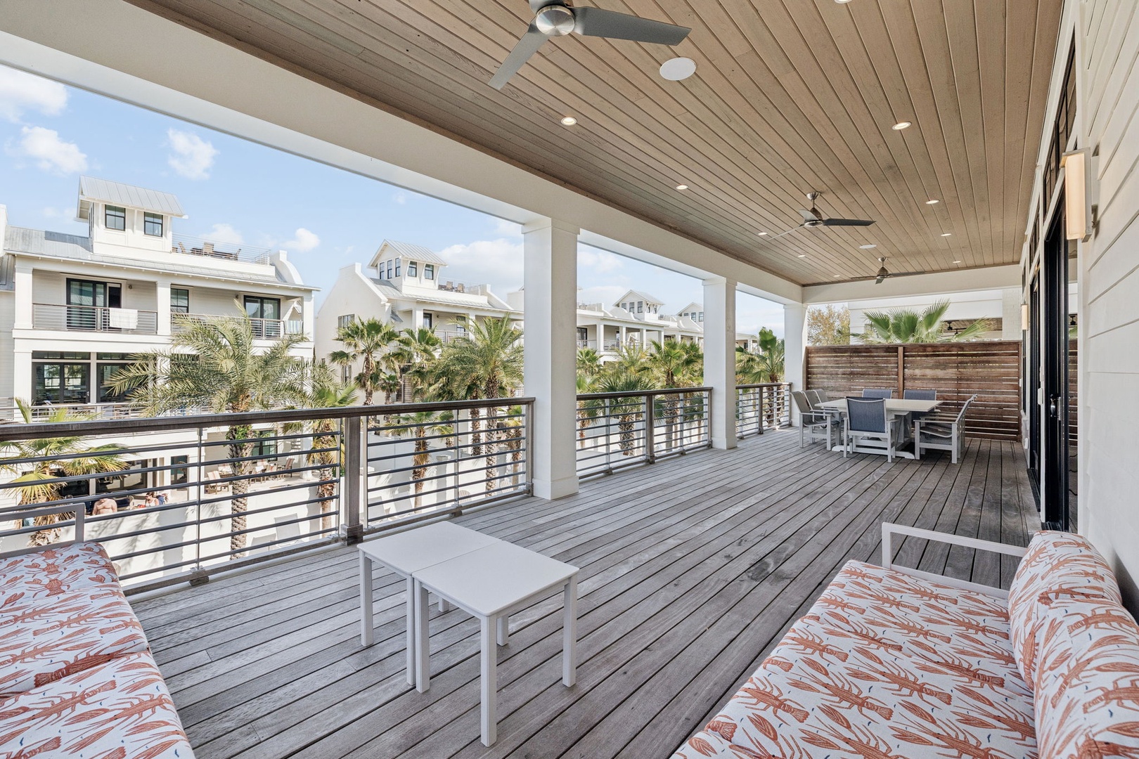 Relax on your expansive covered terrace with comfortable seating and ceiling fans, overlooking tropical palm trees and neighboring homes.