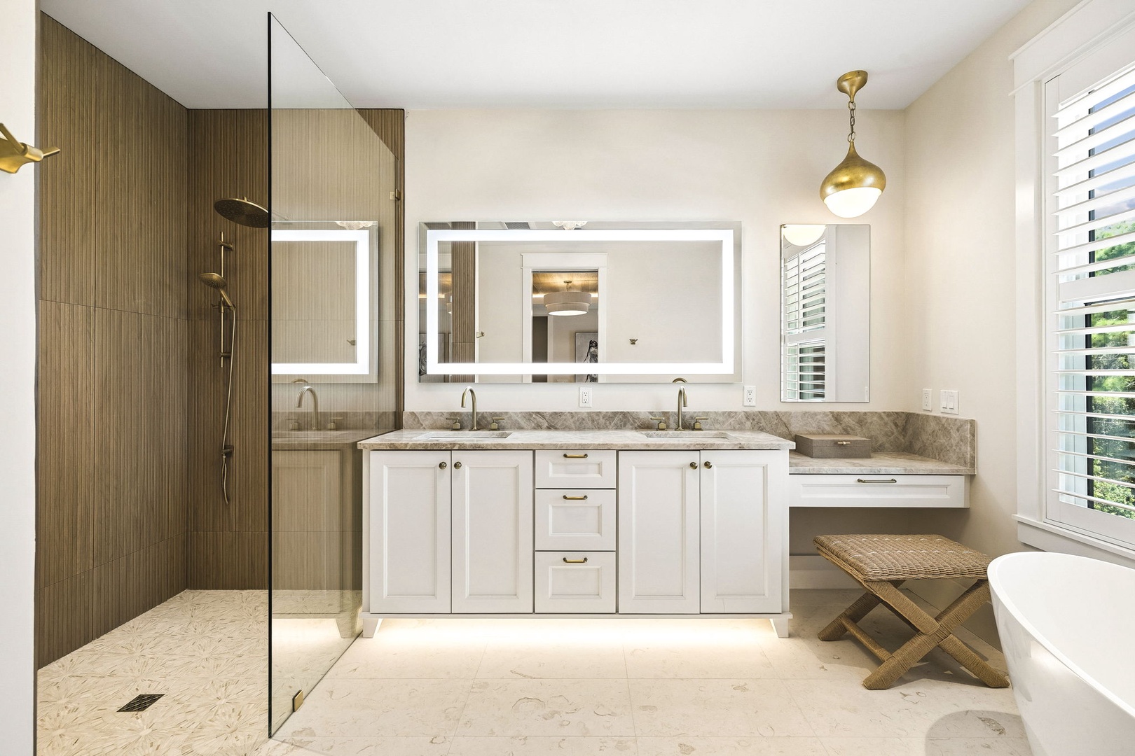 Your luxurious ensuite features a spacious walk-in shower with elegant wood-toned tiles, dual vanities with marble countertops, and beautiful natural light streaming through plantation shutters.
