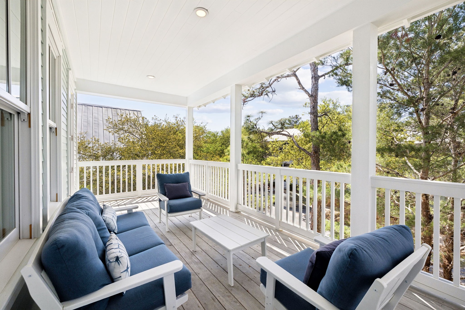 Unwind on your private covered porch with plush blue seating, where morning coffee and peaceful tree views create the perfect retreat.