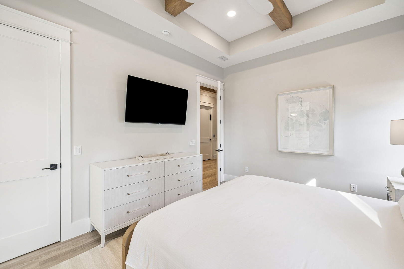 Drift into peaceful sleep in your elegant bedroom, featuring crisp white linens, exposed ceiling beams, and modern amenities for ultimate comfort.