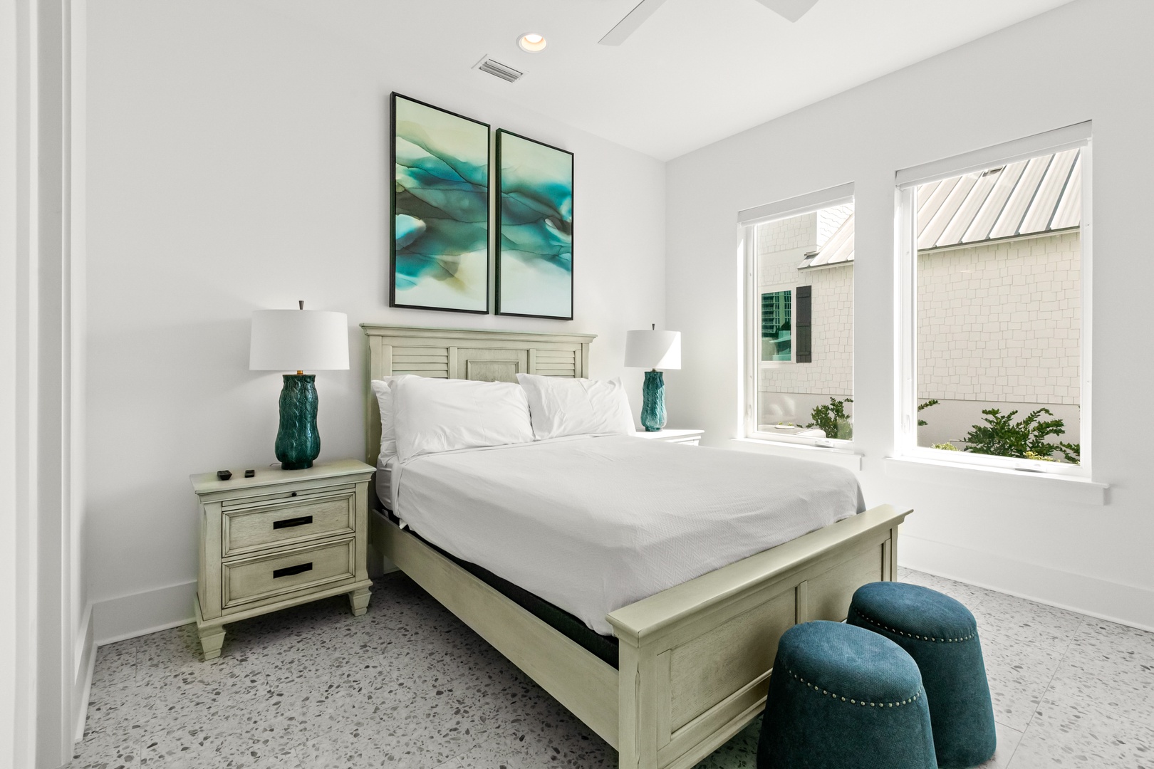 Sink into crisp white linens and drift off in your serene coastal bedroom, where soft blues and natural light create the perfect retreat after a day of adventure.