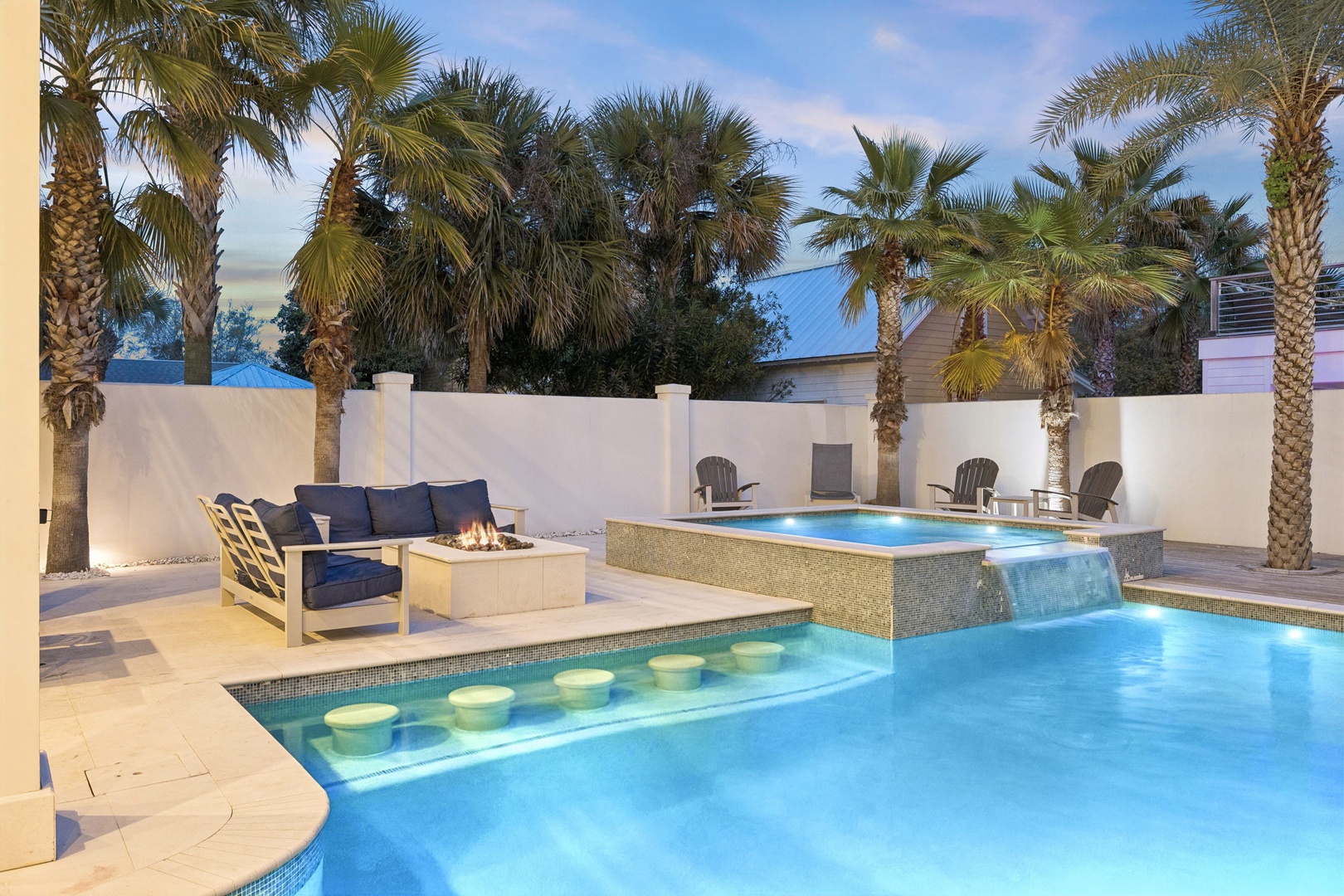 Your private oasis awaits with a stunning pool featuring swim-up bar seating and cozy fire pit lounge beneath swaying palms.