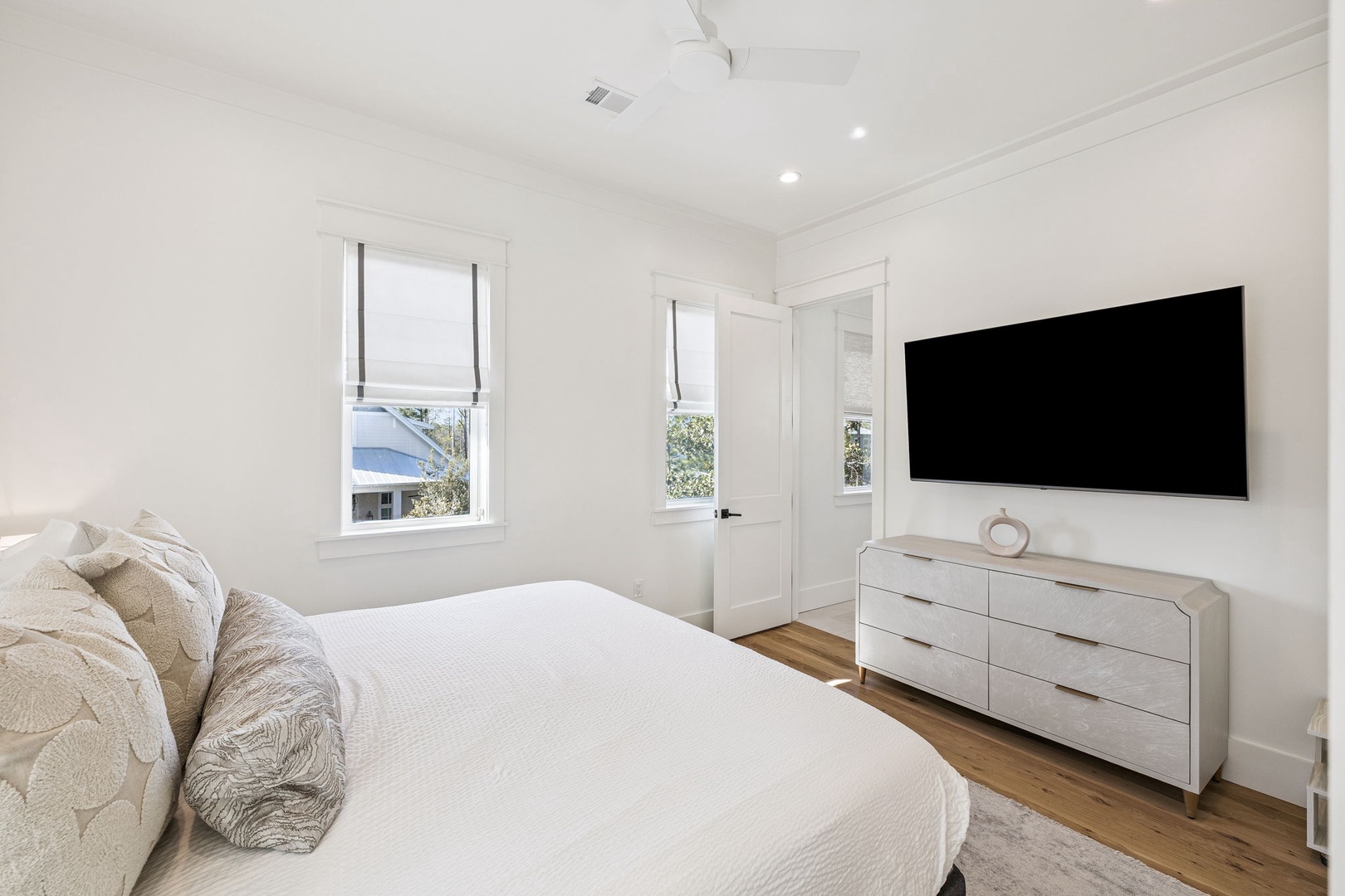 Unwind in your peaceful bedroom with crisp linens, modern dresser, and wall-mounted TV for cozy evenings.