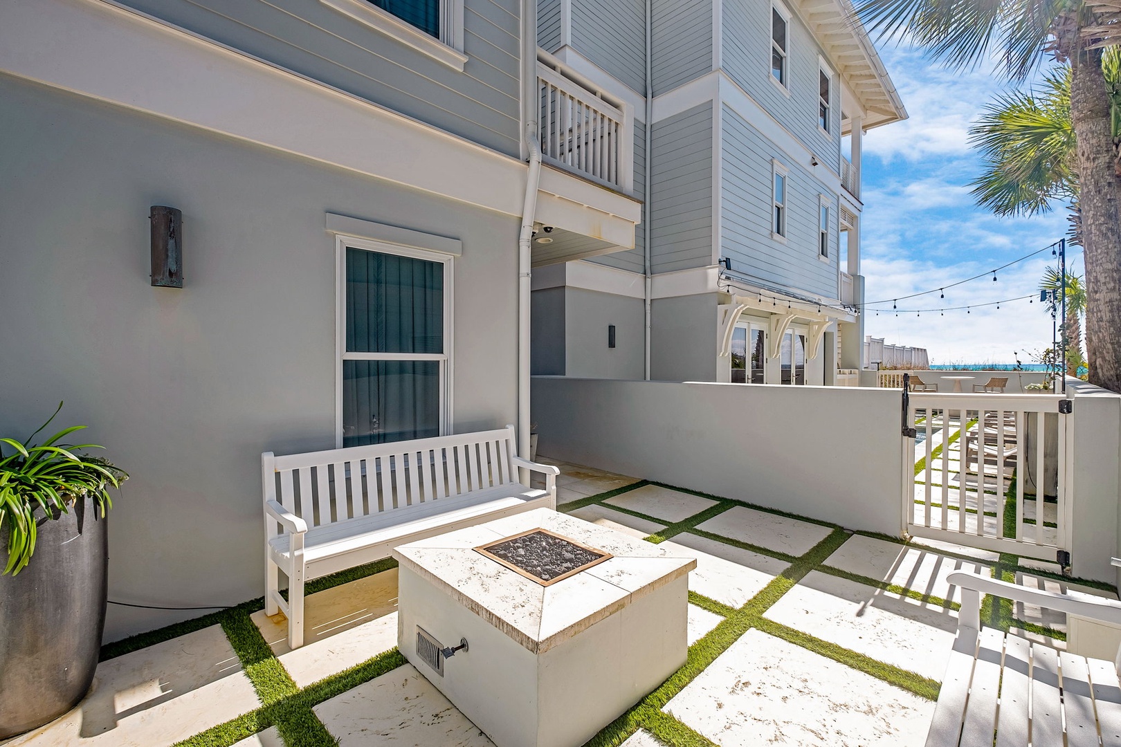 Your private patio invites relaxation with a built-in fire pit, coastal breezes, and tropical palms framing the waterfront beyond—perfect for unwinding after sun-soaked days.