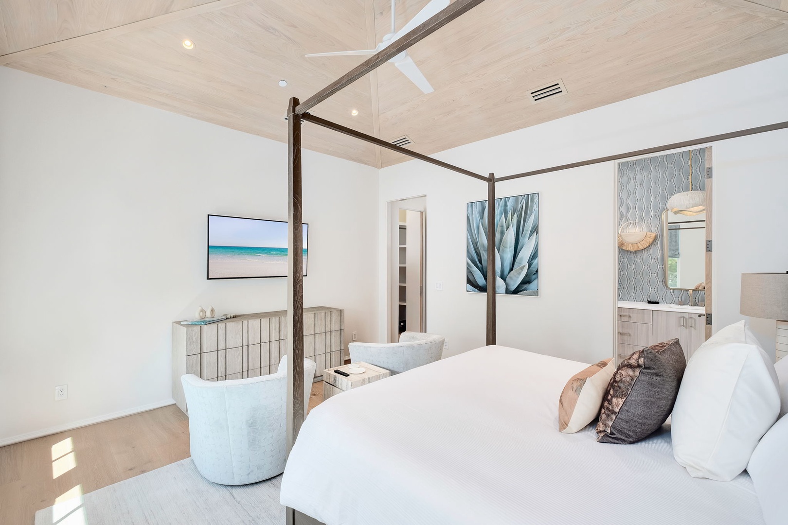 Sink into the plush comfort of your elegant canopy bed, where coastal artwork and soft lighting create a serene retreat for restful nights.