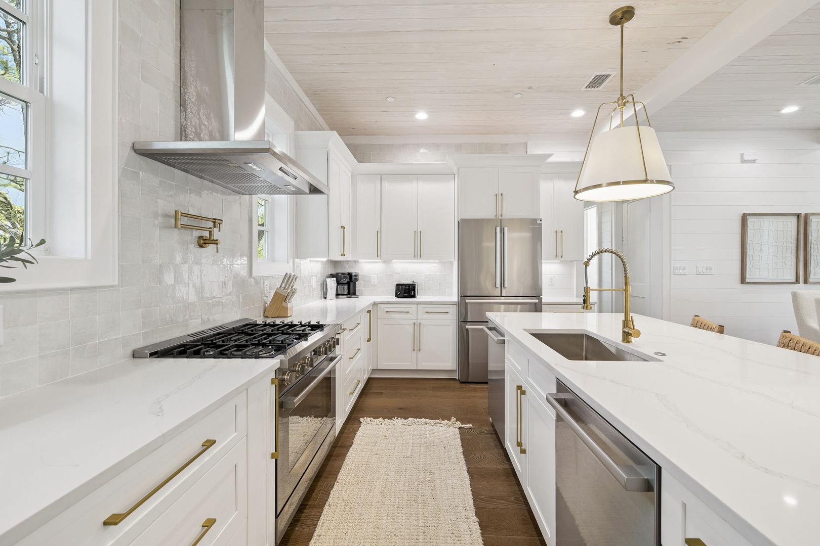 Cook your favorite meals in this bright, modern kitchen featuring gleaming white cabinets, premium appliances, and elegant gold fixtures.