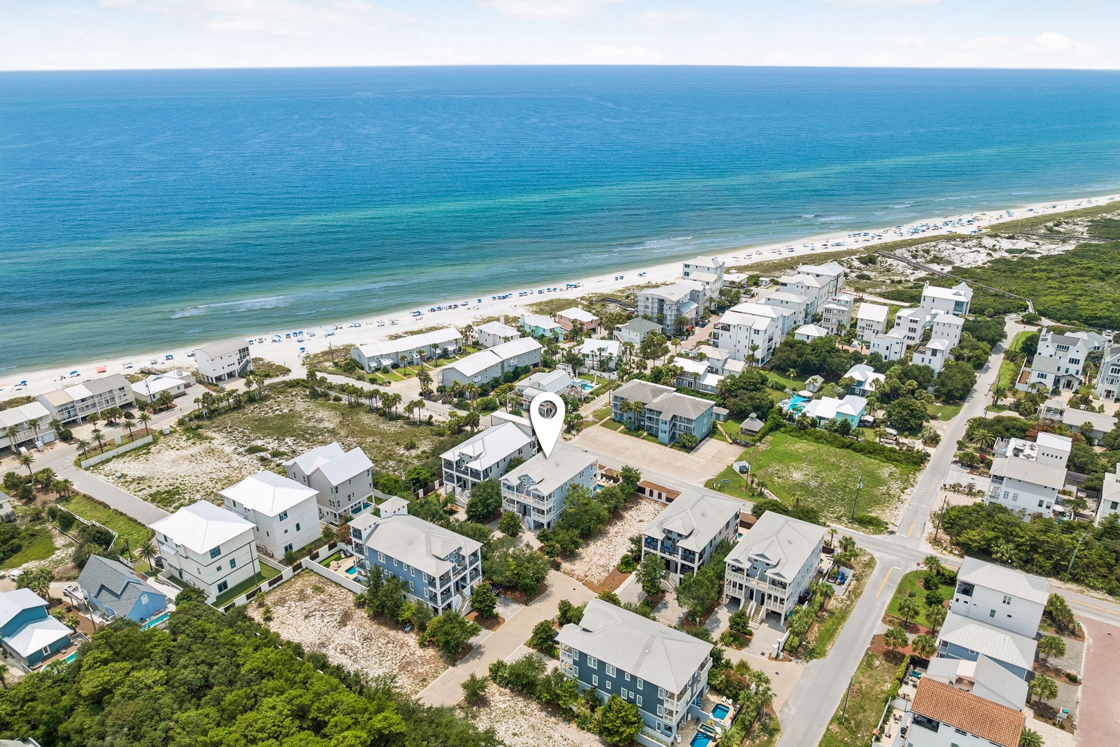 Aerial view of a coastal neighborhood with beachfront properties and nearby ocean access, located within a scenic waterfront community.
