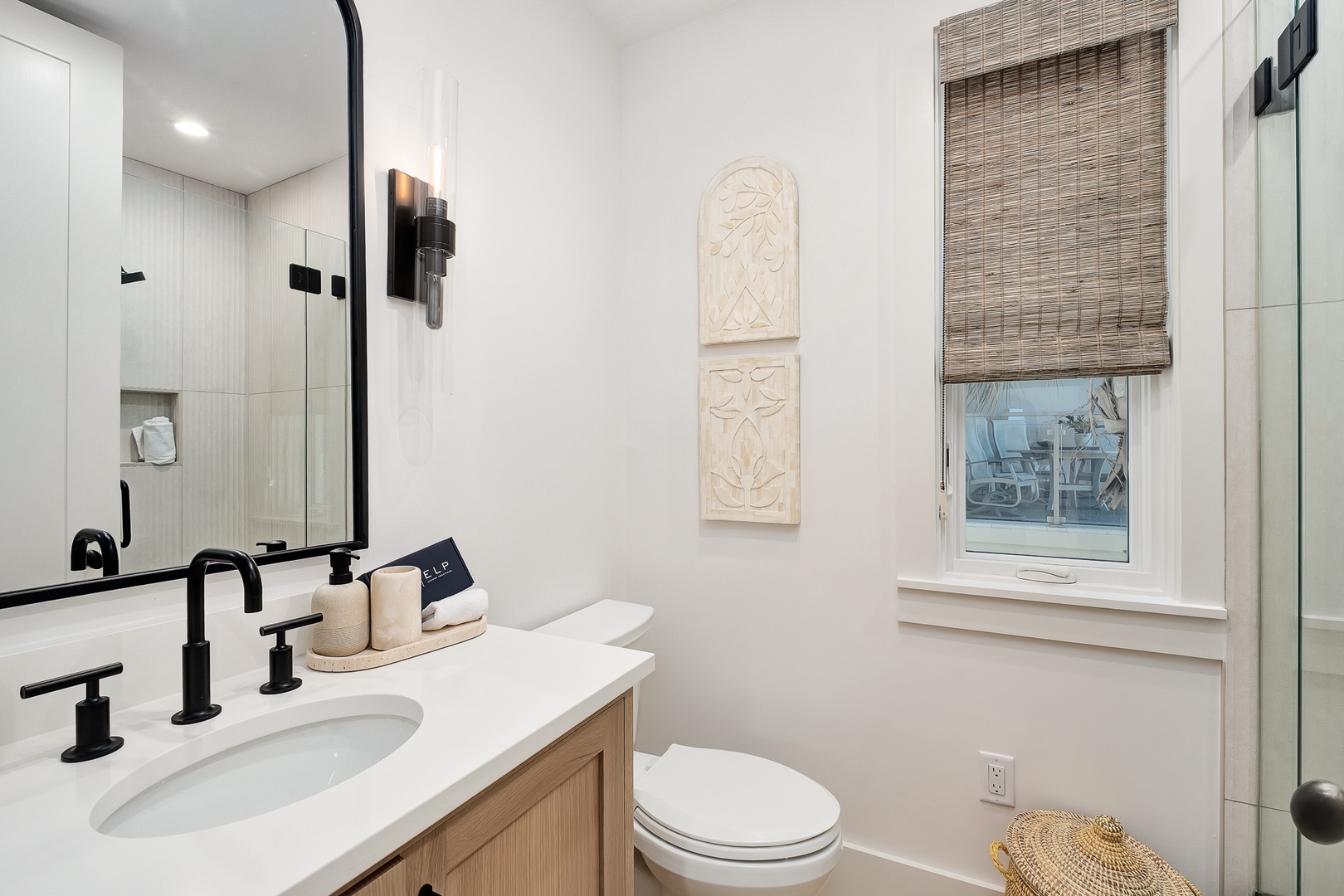 Refresh in your beautifully appointed bathroom featuring sleek black fixtures, warm wood vanity, and natural light streaming through bamboo blinds.