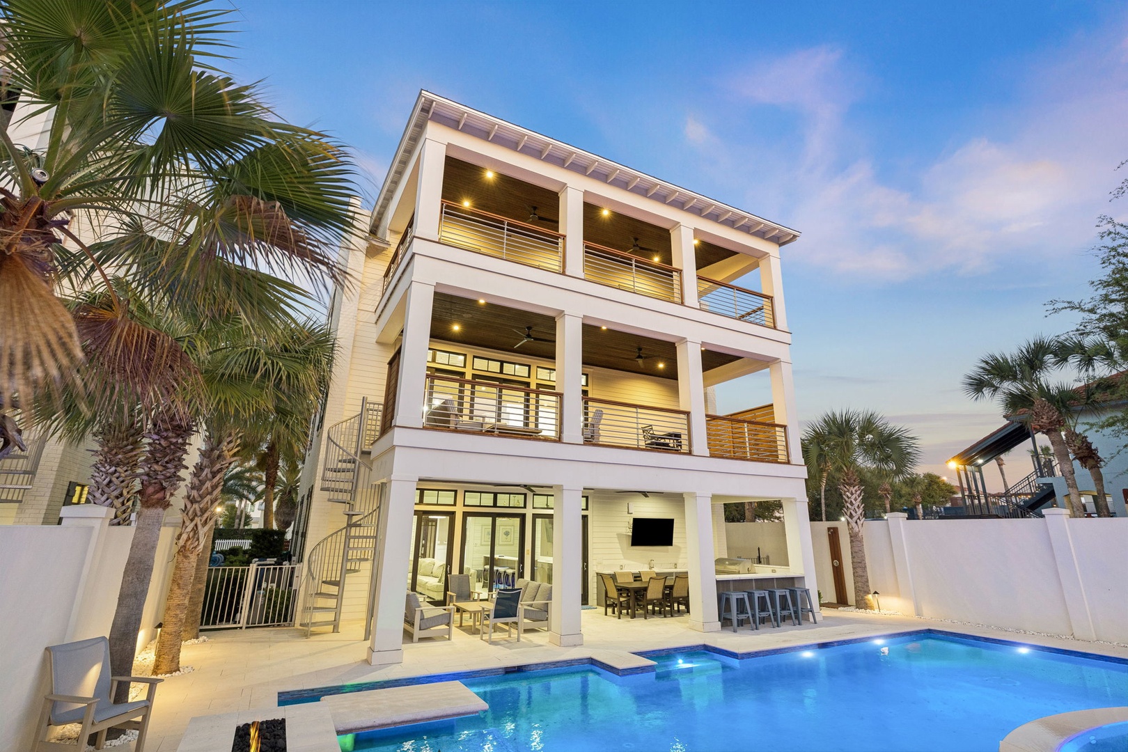 A stunning three-story waterfront home features multiple balconies, tropical palms, and a sparkling pool for an unforgettable coastal retreat.