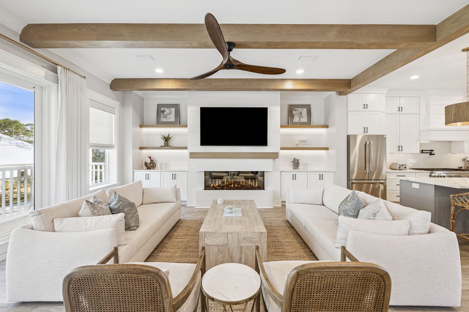 Sink into plush sofas beside the fireplace as natural light floods your elegant retreat with exposed beams overhead.