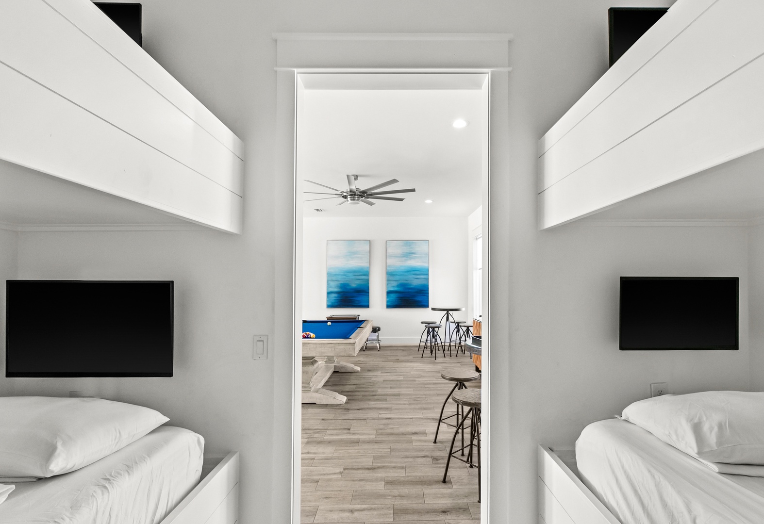 Step into your sleek, modern retreat with crisp white linens and personal entertainment in each sleeping space. Through the doorway, the open living area invites you to unwind and connect.
