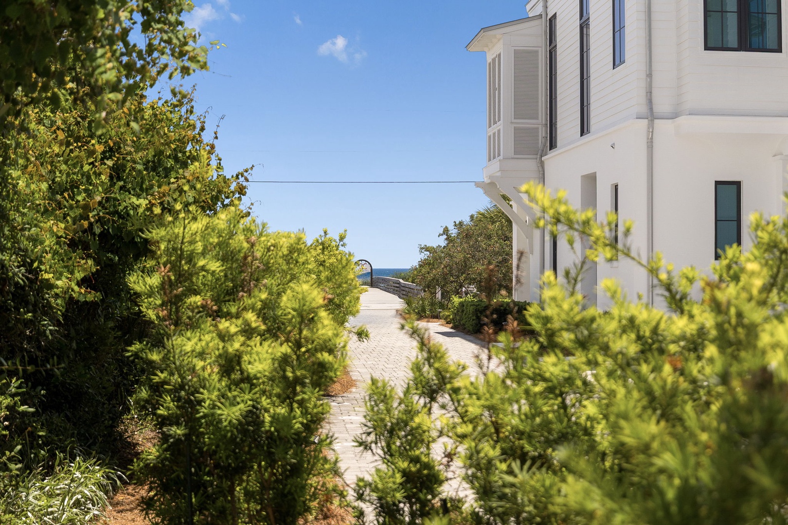 Elegant coastal property nestled among lush greenery with glimpses of the serene blue sea beyond, offering a tranquil Mediterranean-style retreat.