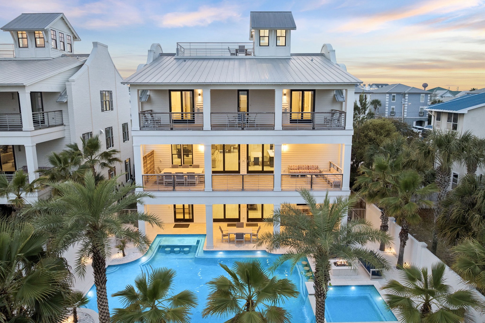 Modern beachside mansion with pristine pool surrounded by tropical palms in an upscale coastal neighborhood.