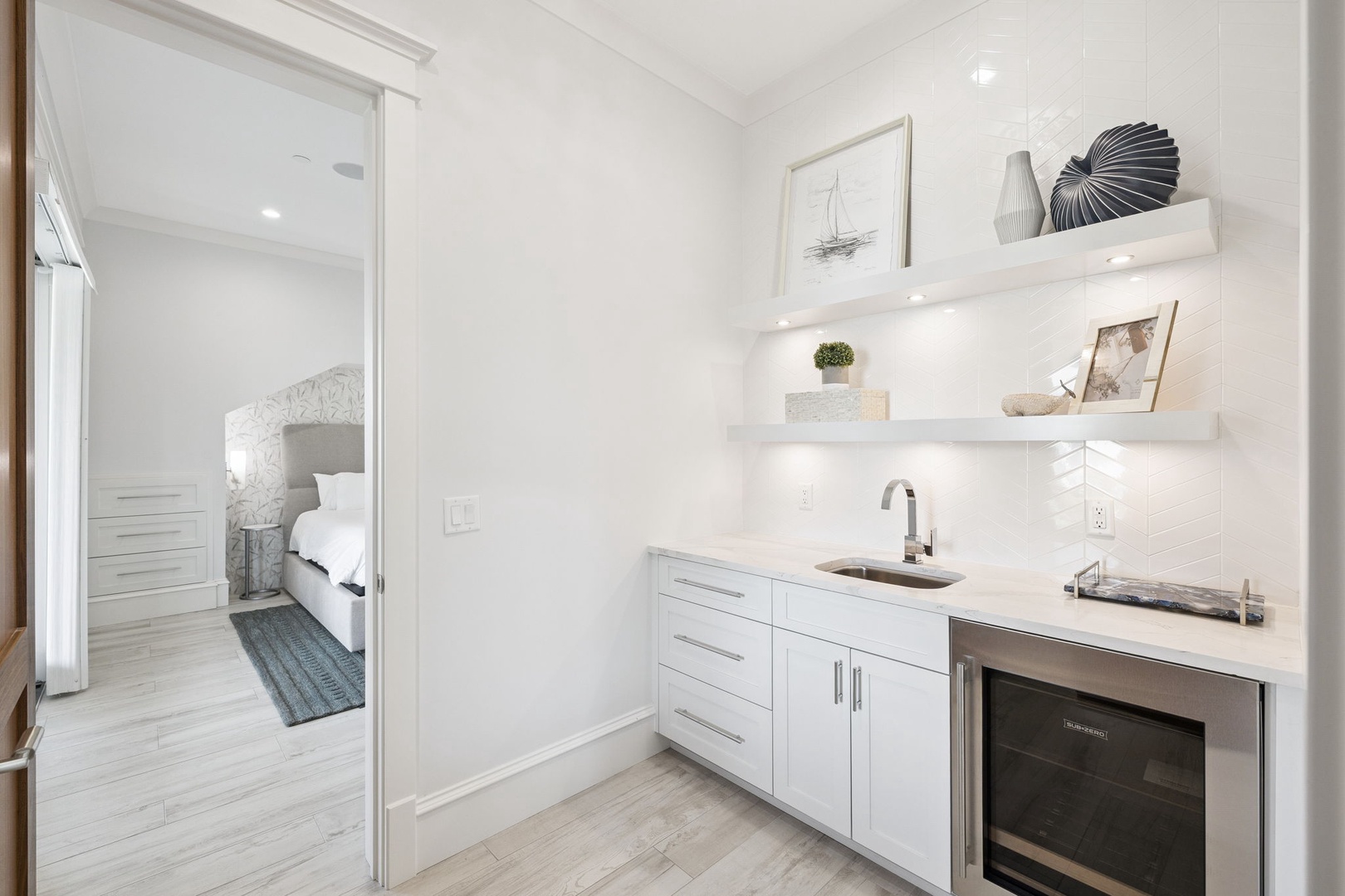 Your sleek white kitchenette offers everything you need with modern appliances and floating shelves styled with coastal touches.