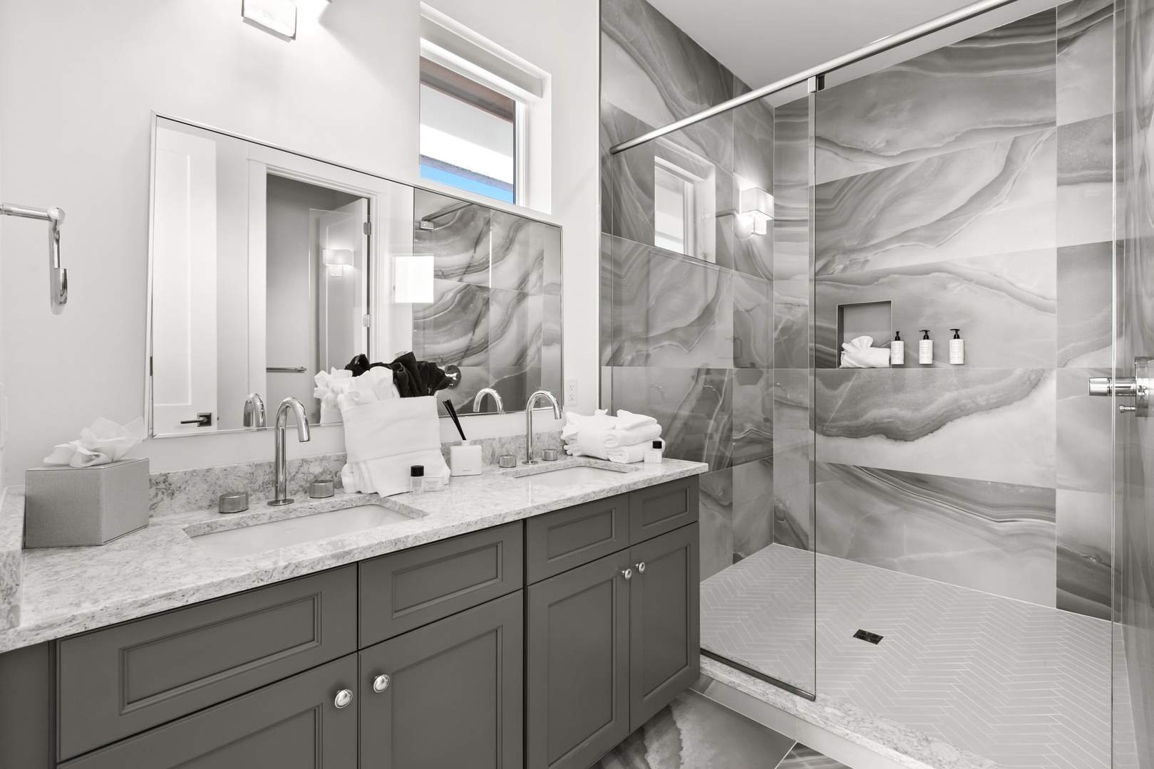 Step into your spa-like bathroom, where striking marble walls meet a spacious glass-enclosed shower and elegant dual vanities—your personal sanctuary of luxury and relaxation.