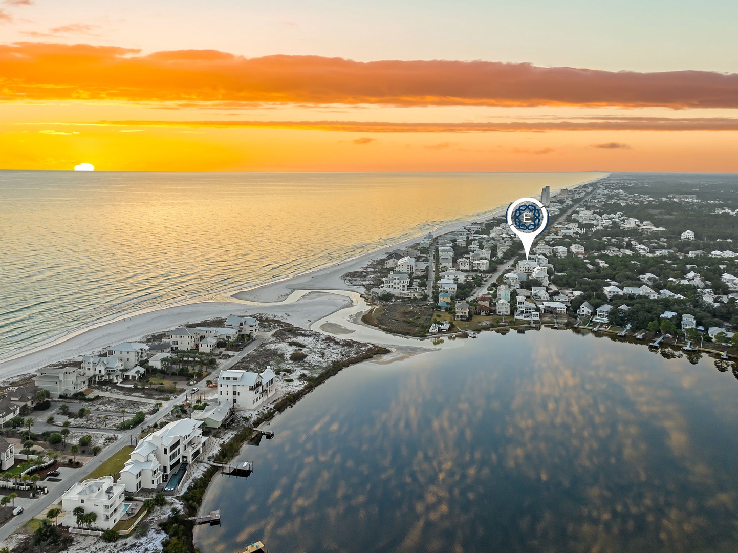 Spectacular aerial view of beachfront community during golden sunset, showcasing pristine coastline and nearby residential area.
